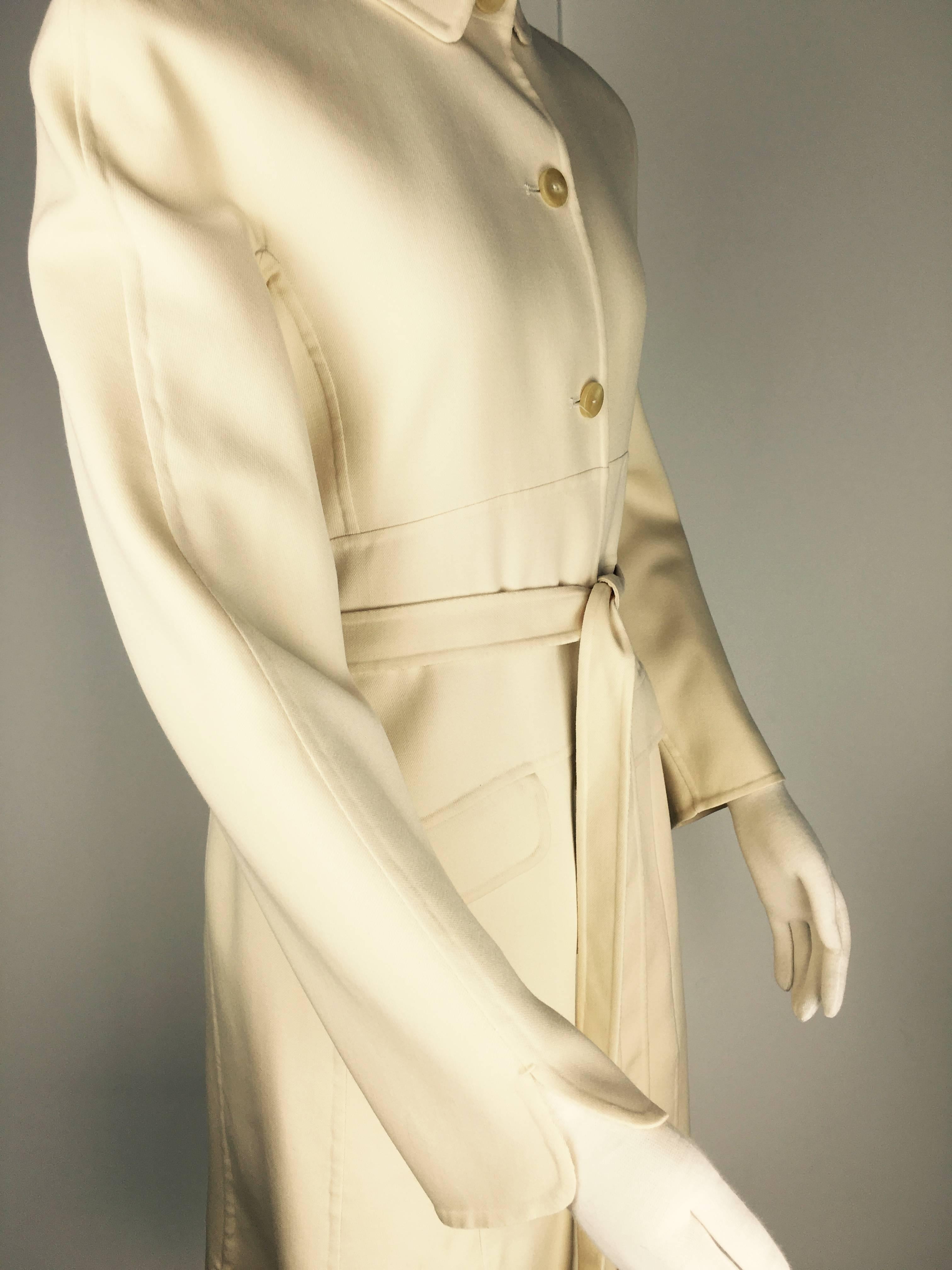 Classic Chado Ralph Rucci belted cream wool coat. Notched sleeves, 
flap pockets and top stitched midriff bands. Separate belt that can be tied around the waist; trench-coat style.  Gorgeous smooth polished buttons.
A piece of incredible