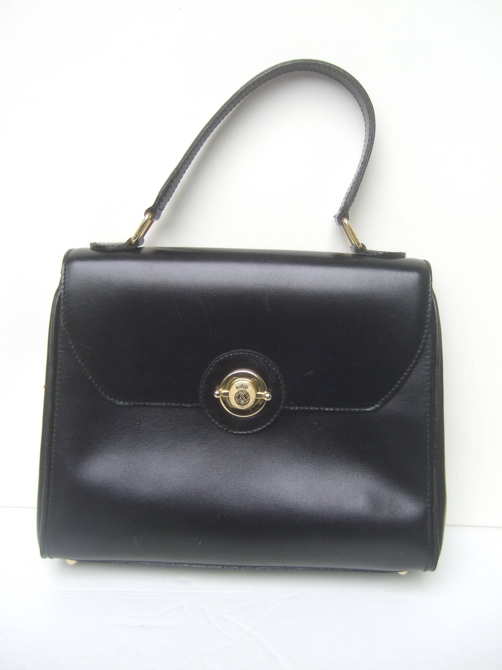 Saks Fifth Avenue Ebony leather handbag
The chic Italian handbag is designed
with supple black leather on the exterior

Adorned with a sleek gilt metal clasp
mechanism with a small crown symbol
The clasp is inscribed Honi - Soit -Oui 
Mal .Y.