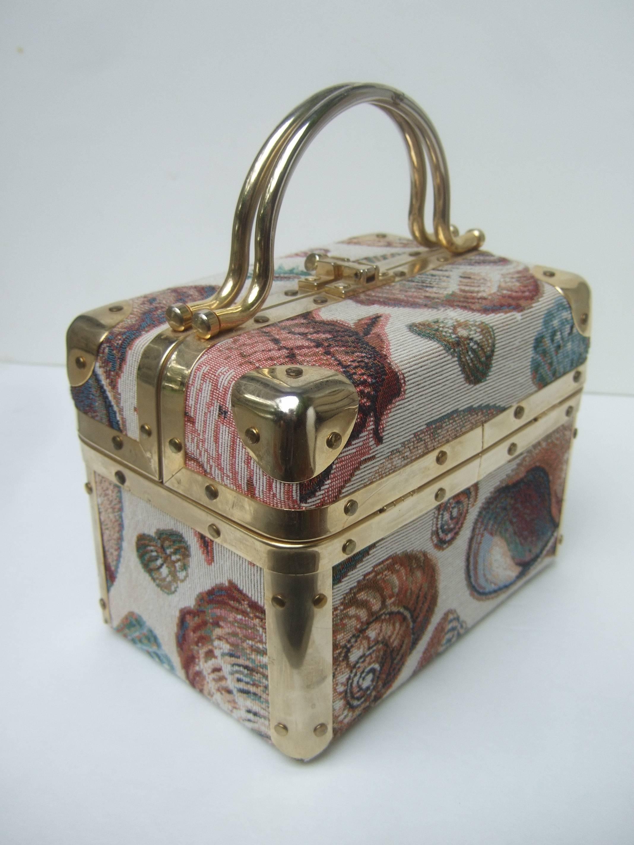 Sea Life tapestry train case handbag
The stylish handbag is covered with 
cloth covering illustrated with a 
collection of various types of sea 
shells on all sides 

The posh handbag is designed with 
gilt metal swivel handles and