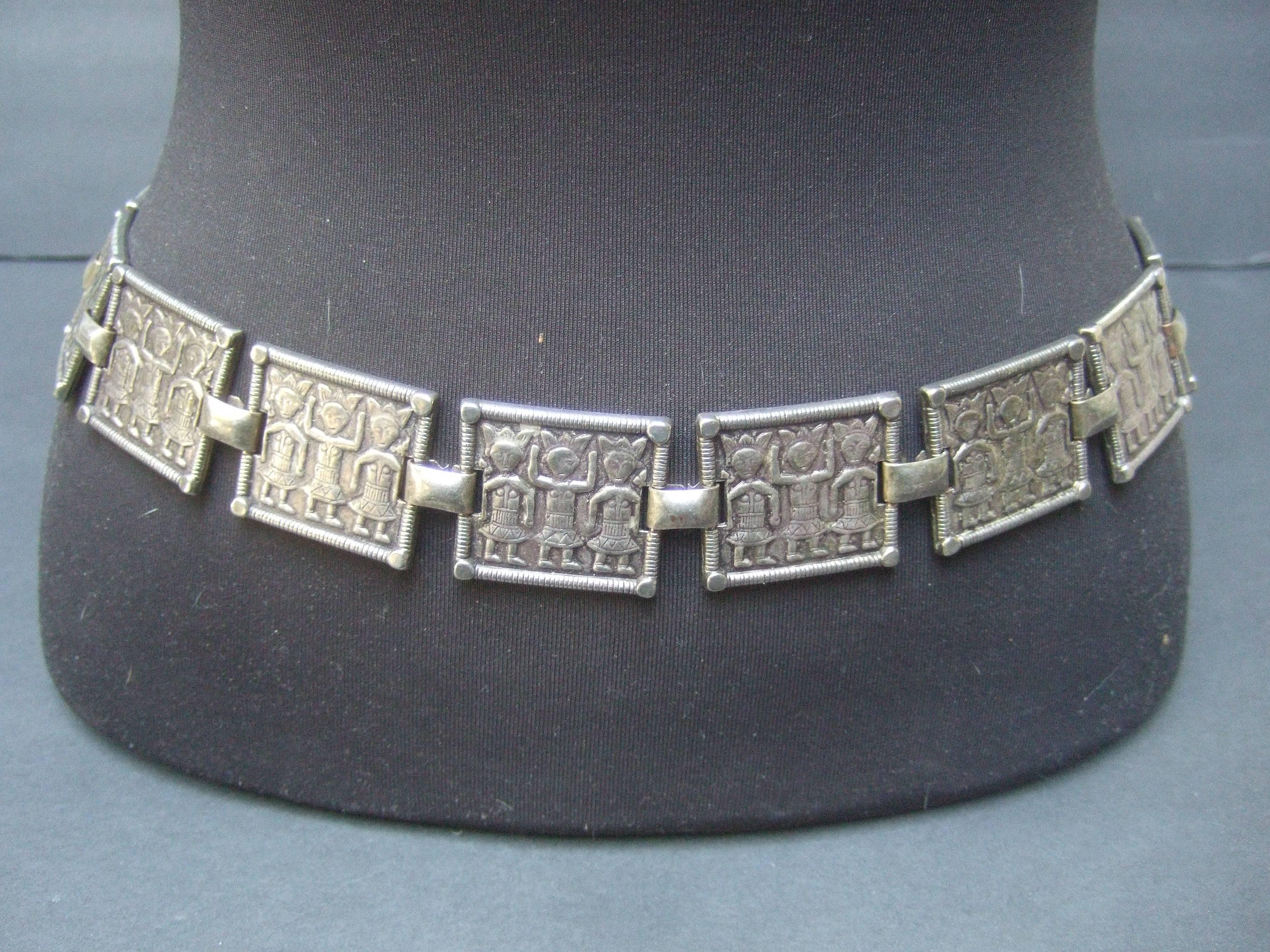 Exotic tribal figure pewter tone metal link belt c 1970s
The unique belt is designed with a series 
of hinged square metal tiles

Each link depicts a trio of tribal warrior figures
The series of pewter tone metal links are solid
and