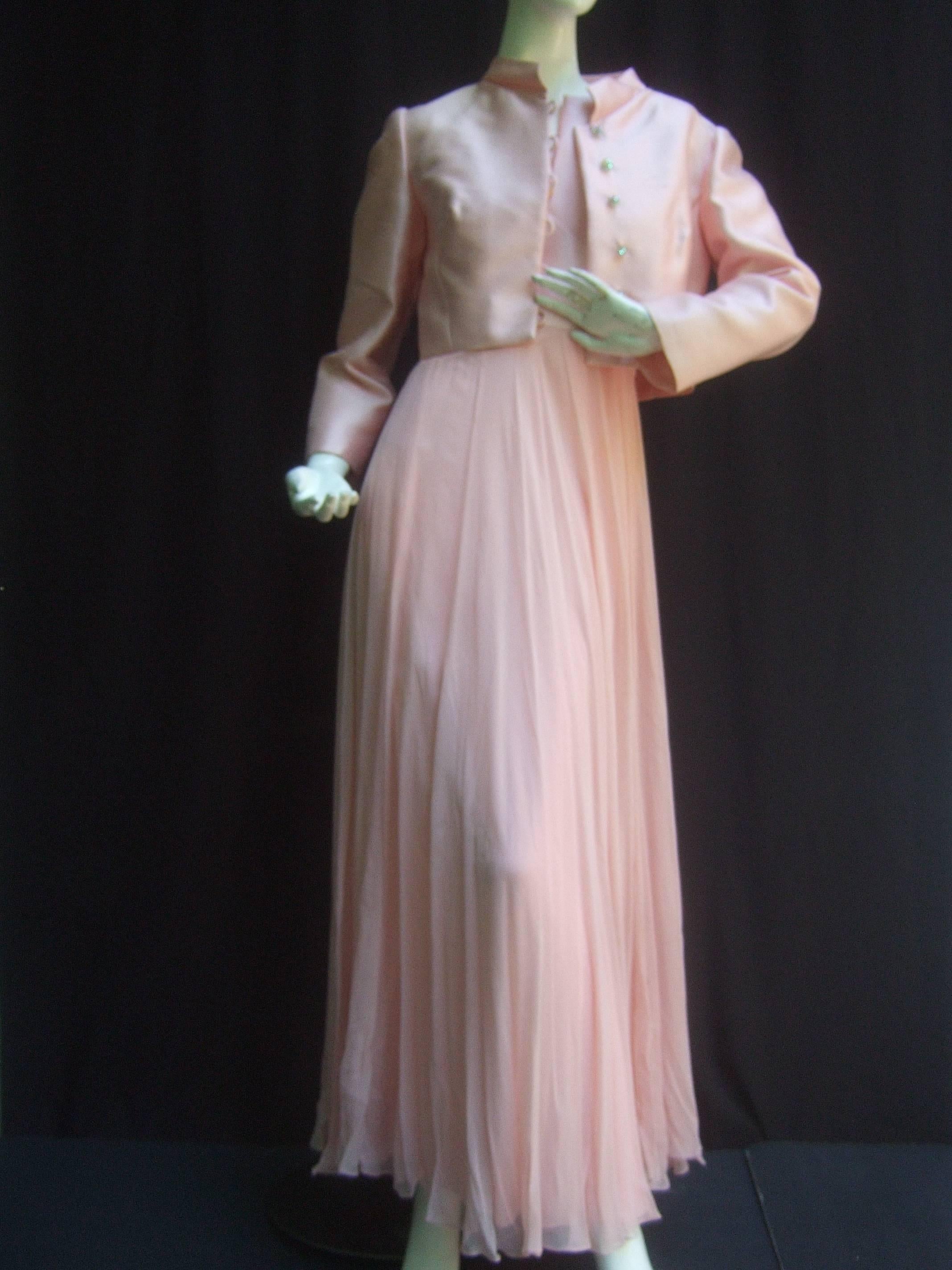 Elegant pink shantung silk chiffon jacket / gown ensemble c 1960
The chic bolero jacket is designed with luminous pale
pink silk shantung with a row of glittering diamante 
crystal buttons and stand up collar 

The ethereal gown is designed