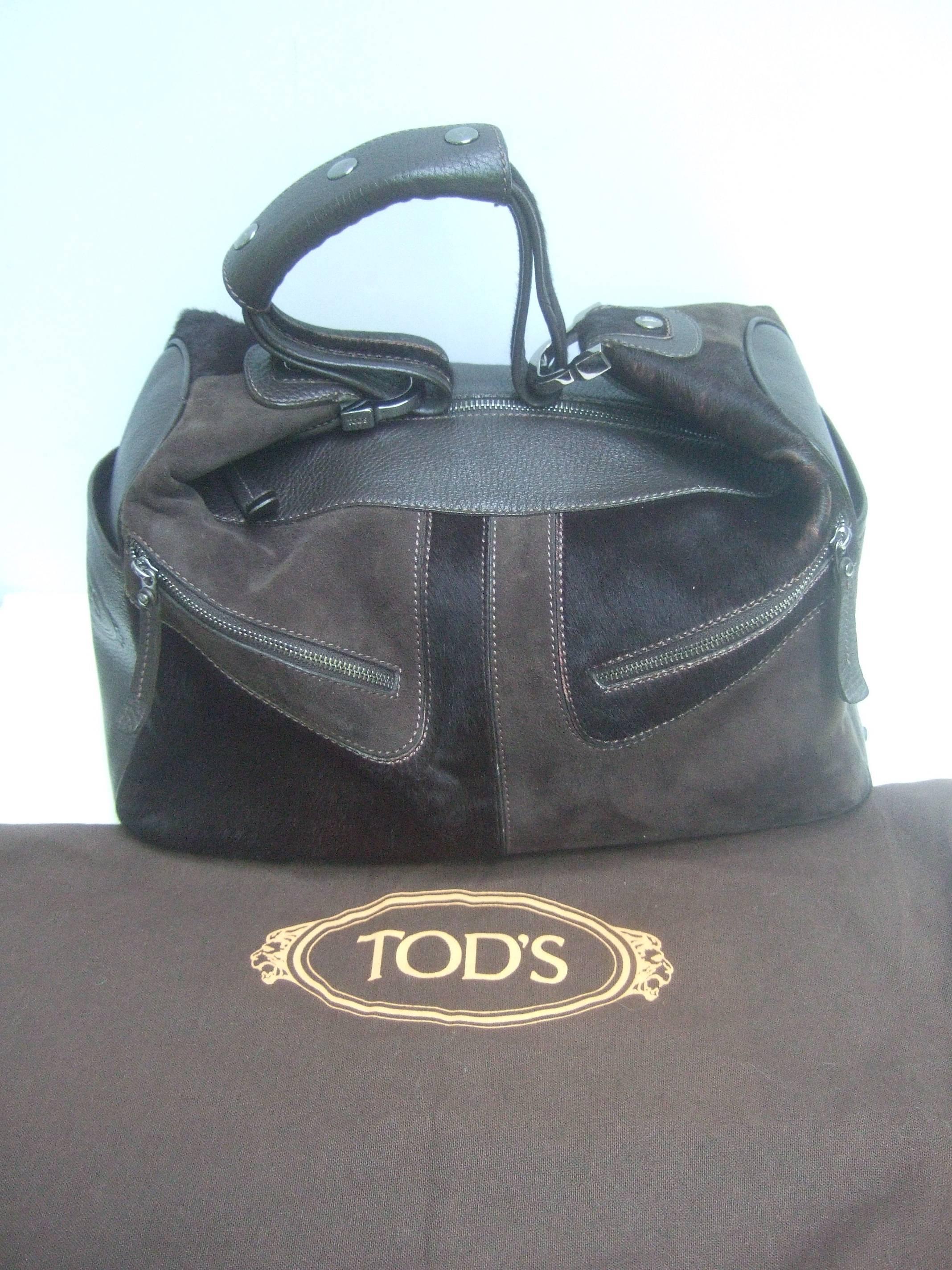 Tod's Chocolate brown leather pony hair handbag
The stylish designer handbag is partially covered
with supple brown leather with a pebble leather 
finish accented with brown suede panels 

The exterior panels are covered with dark brown 
pony