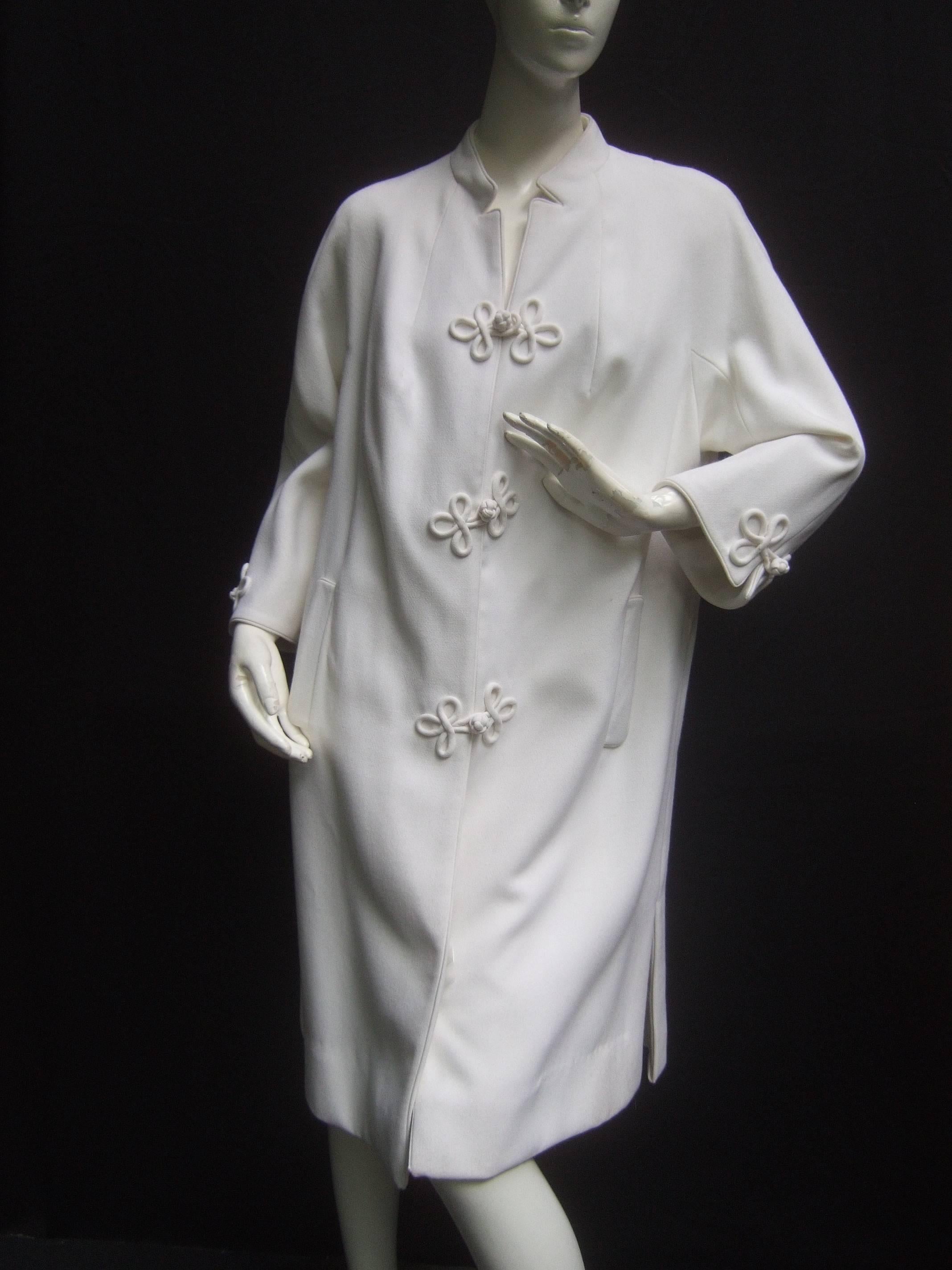 Crisp white frog button coat from Hong Kong c 1970s
The chic retro coat is designed with large frog
style closures that run down the front and extend
to both sleeves

The severe minimal design is enhanced with the
juxtaposition of the looped