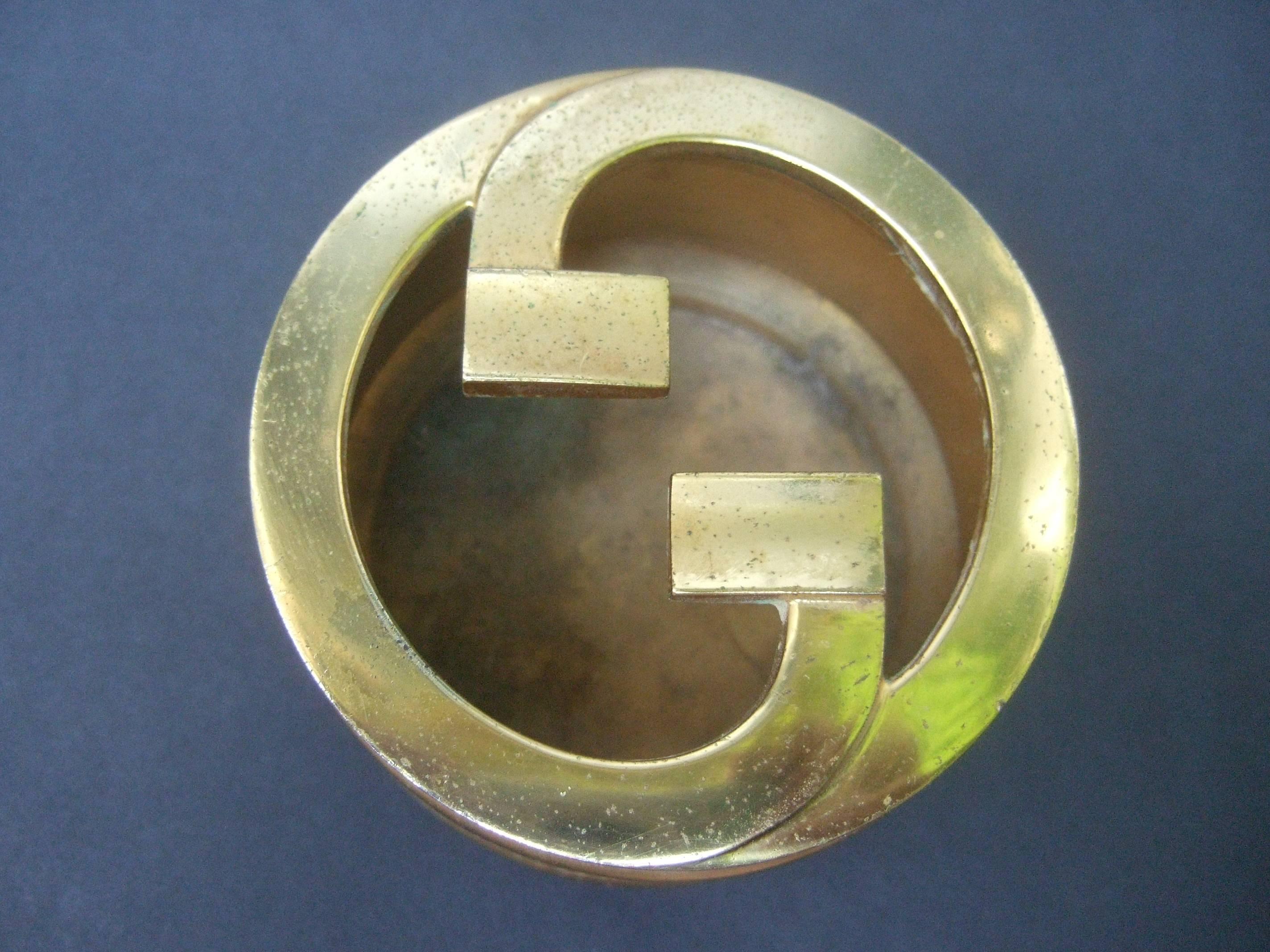 Gucci Sleek gilt metal G.G. initial ash tray c 1970s
The elegant Italian ash tray is designed 
with Gucci's massive gilt metal interlocked
G.G. initials

The sides of the ash tray are covered with
Gucci's signature brown coated canvas