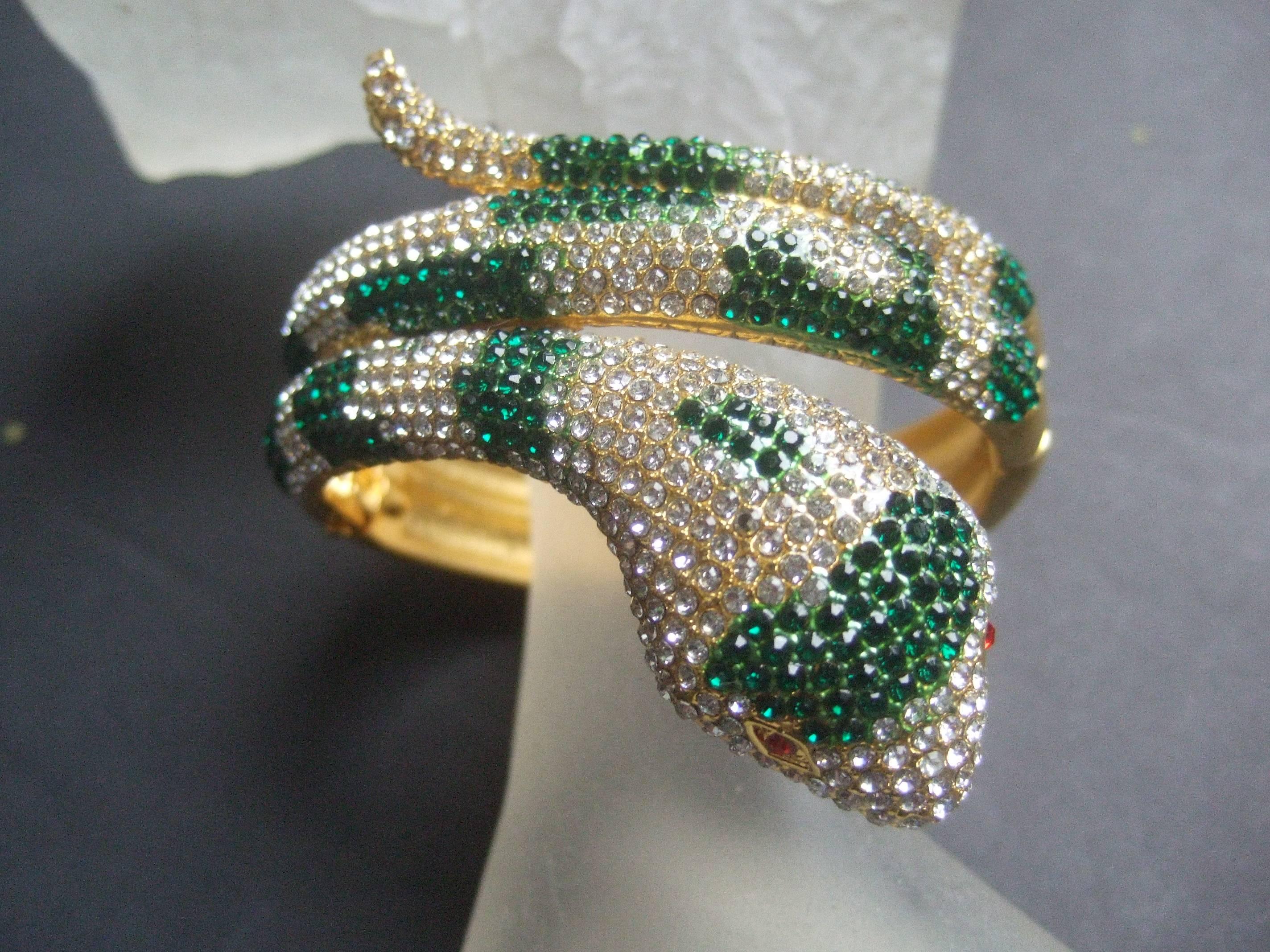 Glittering crystal hinged serpent bracelet 
The unique bracelet is designed with coiled
serpent encrusted with brilliant diamante 
& emerald green color crystals

The serpent's eyes are distinguished with 
ruby red color crystals. The hinged