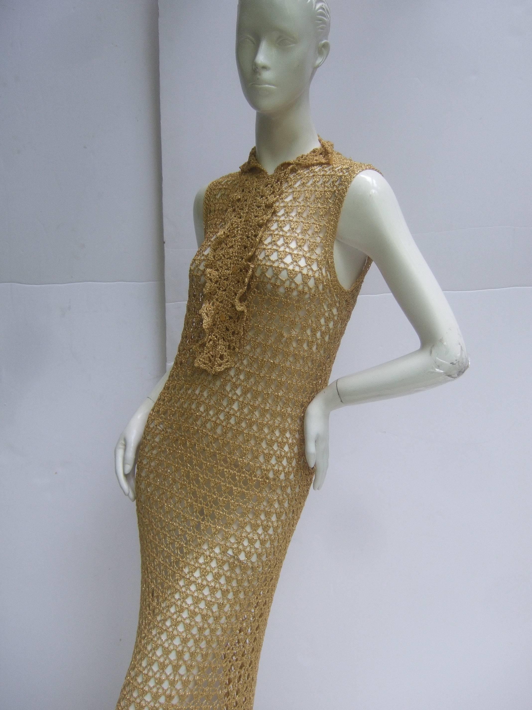 Incredible 1960's gold metallic crochet gown. Curvaceous, slinky cut.
Ruffles at the neck, flattering flared hemline. Made of soft gold metallic crochet
thread.  Unlabelled. Very good condition. Length: 72