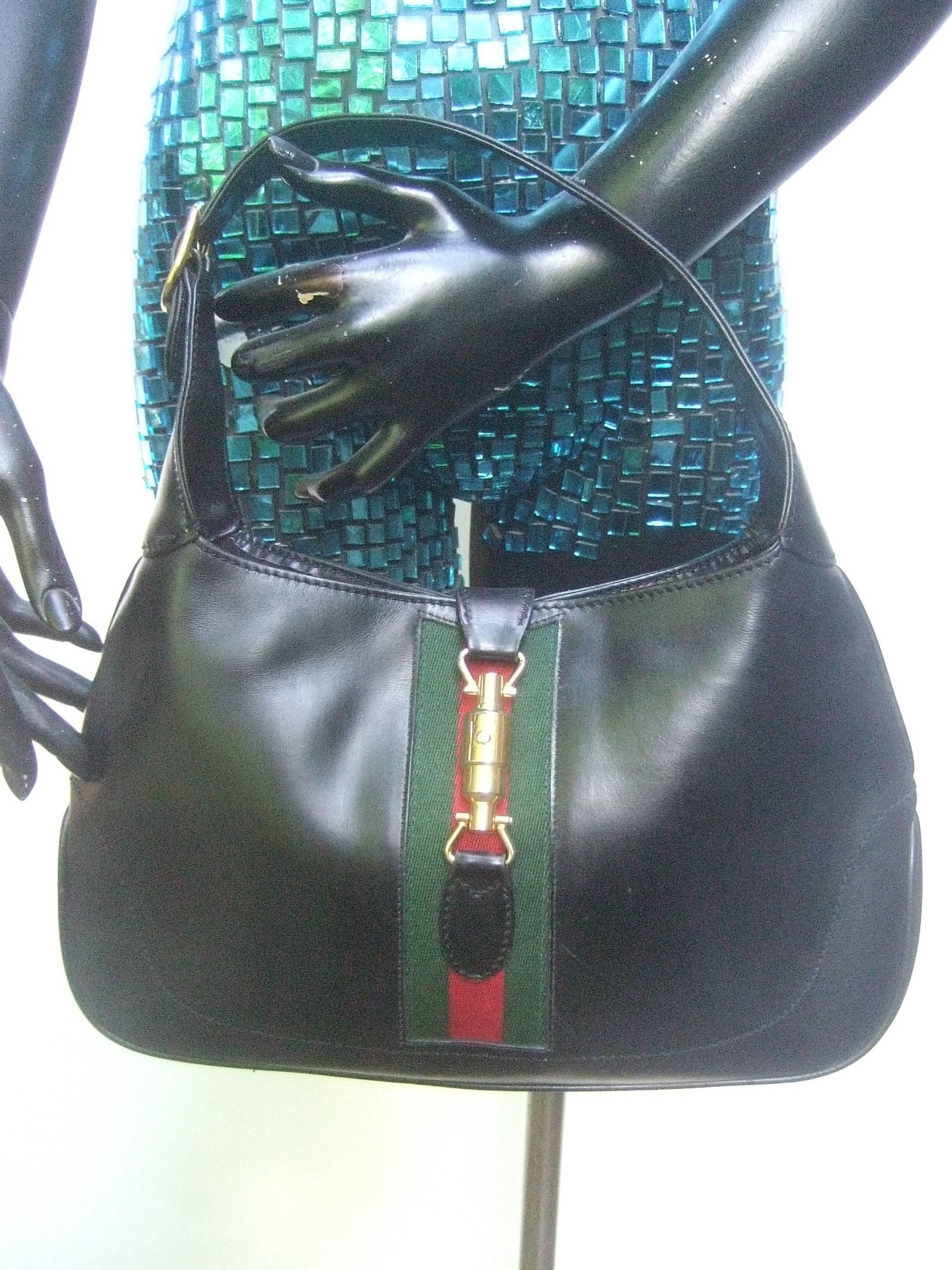Gucci Italy Iconic ebony leather Jackie O piston handbag c 1970s
The classic Gucci handbag is covered with supple black
leather; designed with a sleek gilt metal piston clasp 
mechanism

Underneath the gilt metal piston clasp is Gucci's