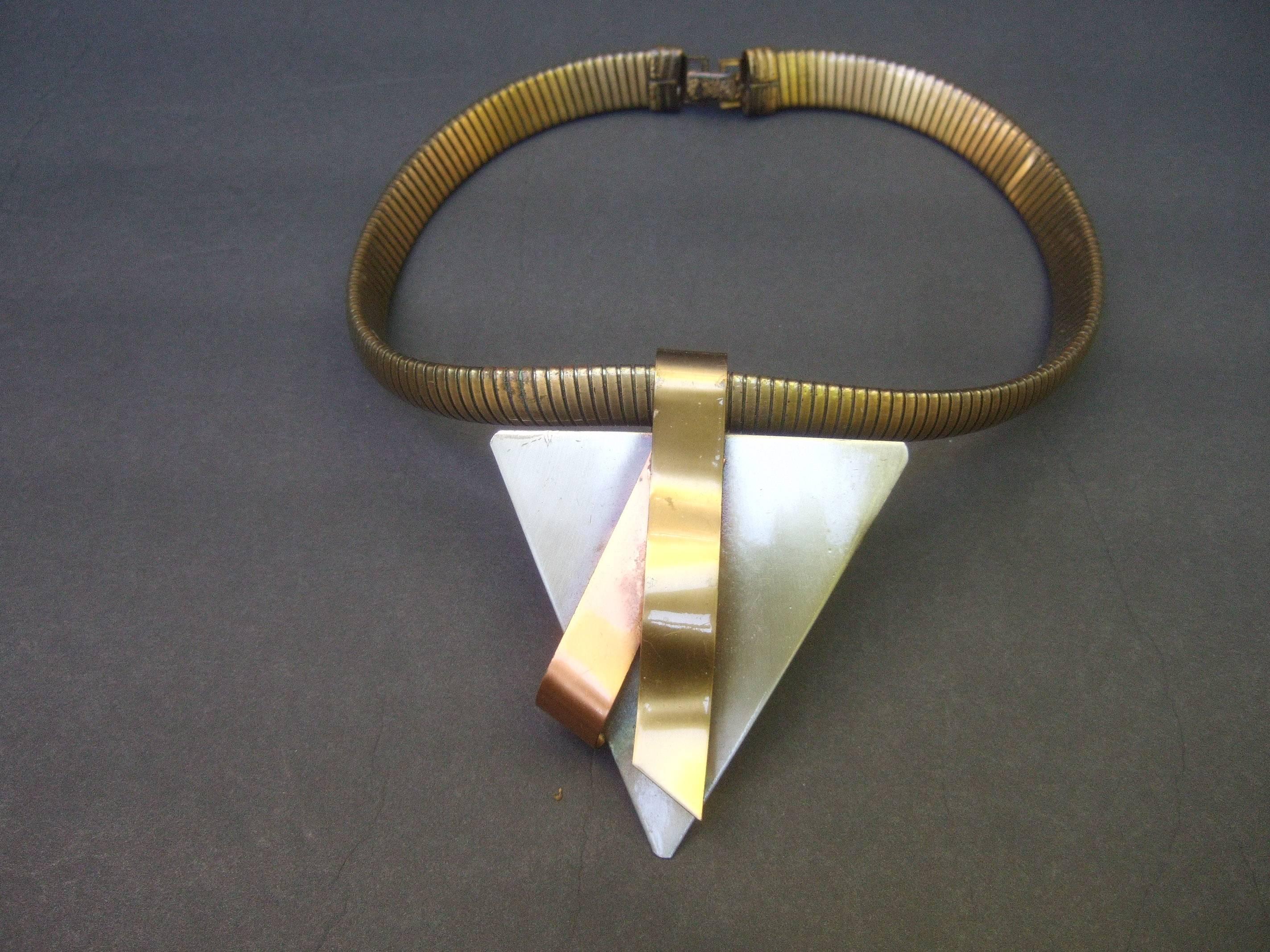 Brutalist mixed metal industrial choker necklace c 1990s
The severe bold artisan choker is designed with a large 
triangular metal pendant. The large pendant is 
designed with a darkened silver tone patina;
juxtaposed with two sinuous metal
