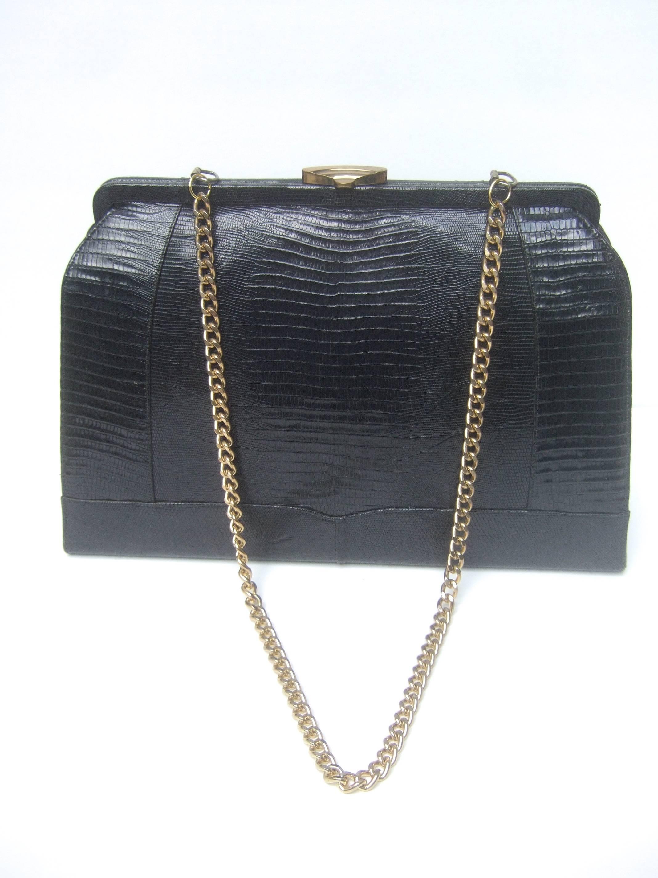 Sleek ebony lizard skin structured large handbag c 1960
The stylish retro large scale shoulder bag is covered
with lacquered lizard skin 

The clasp and shoulder strap chain are gilt metal
The interior of the shoulder bag is lined in black