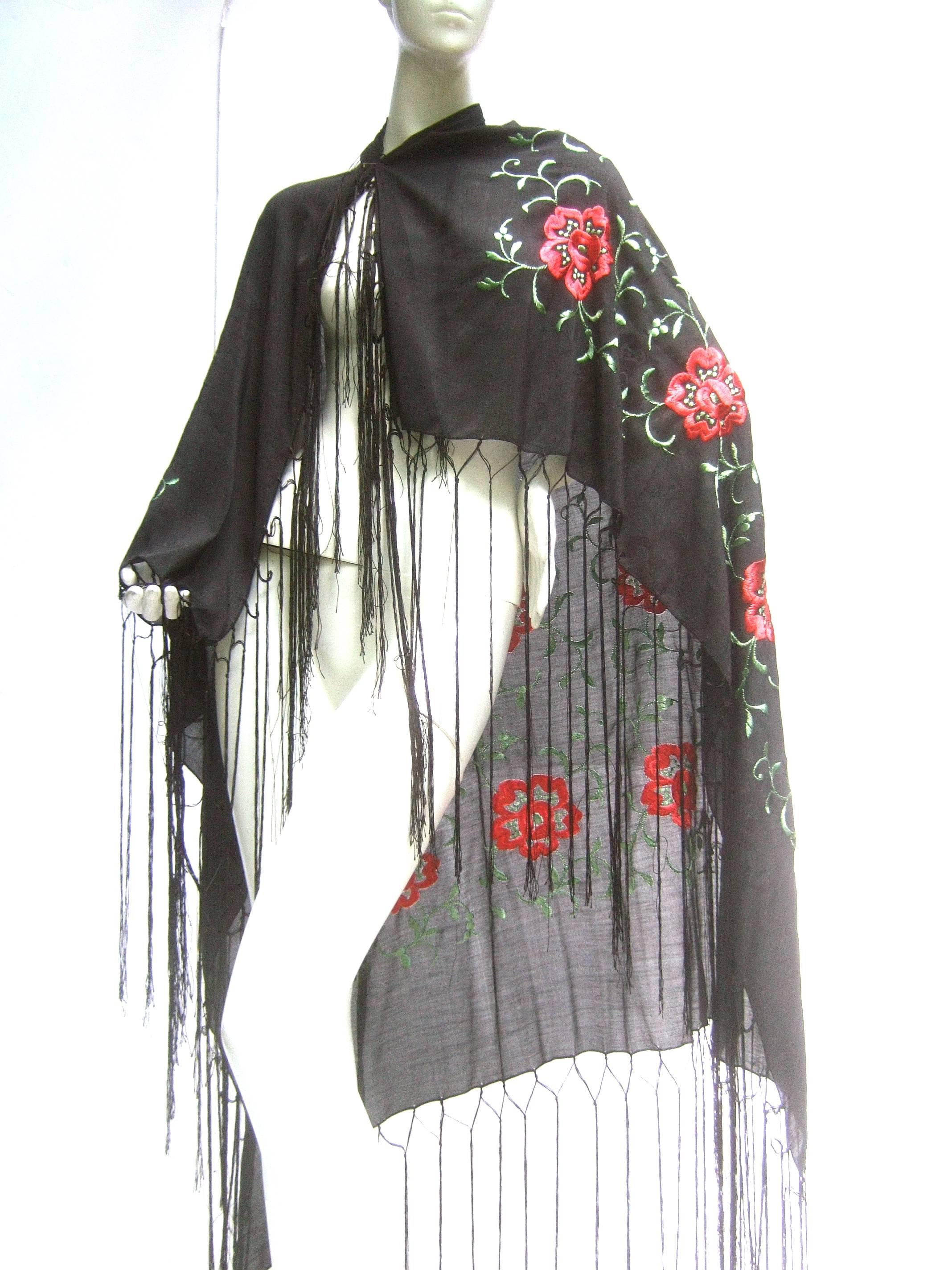 Exotic embroidered black floral fringe silk shawl c 1960 
The elegant fringe shawl is embellished with a 
series of red embroidered flowers accented 
with sinuous embroidered green leaves 

The sheer light weight silk fabric has a luxurious
