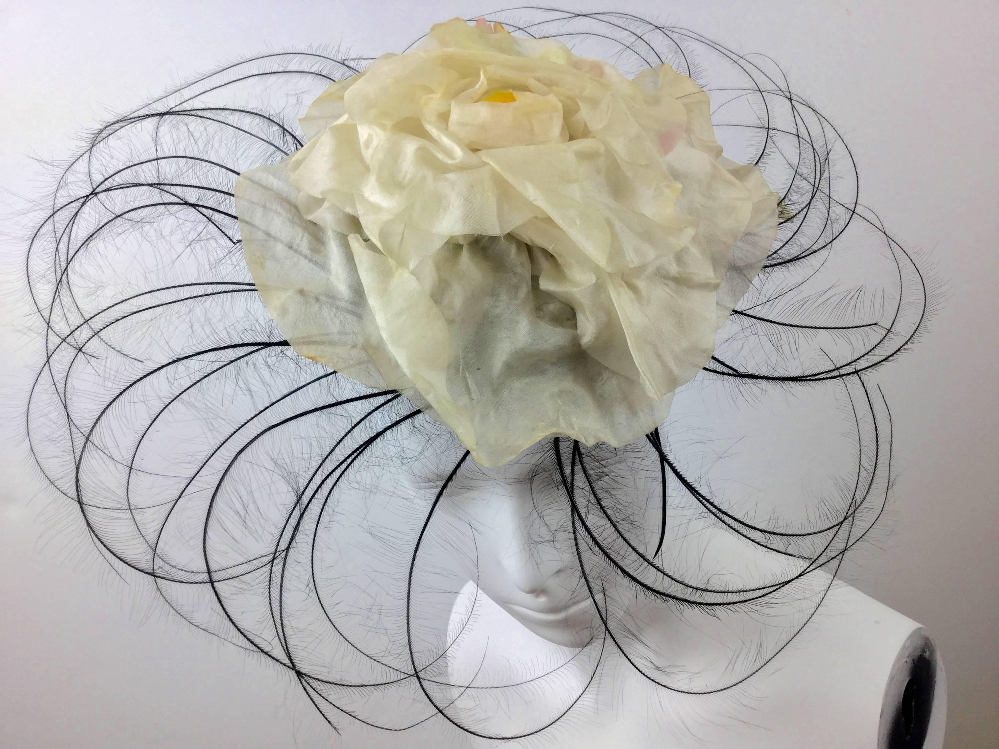 Incredibly rare Bes Ben pinwheel hat. A spiral of shaved black feathers radiate from a central off-white silk camellia with subtle hints of pink and green underneath. There are more feathers at the front and sides than at the back. 

It is designed