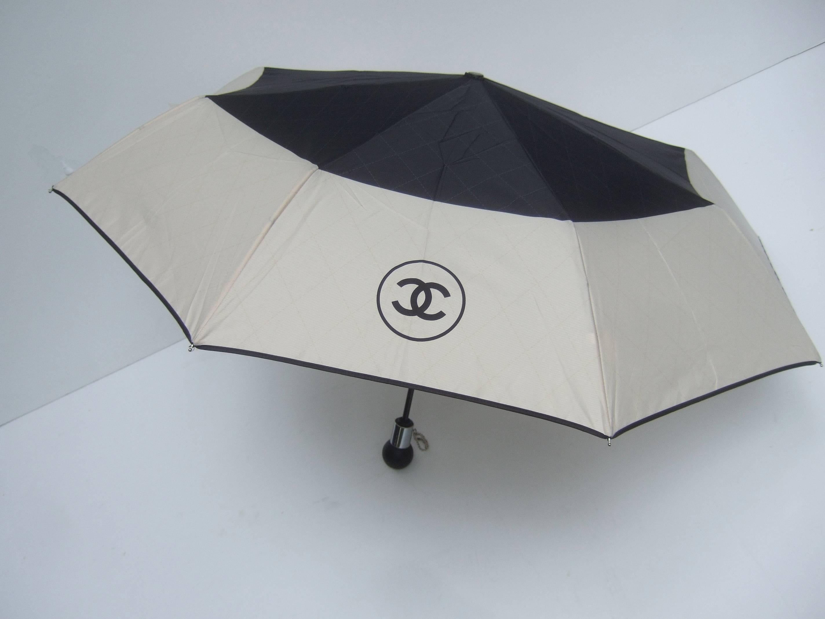 Chanel Stylish black and tan nylon umbrella in Chanel Box
The chic umbrella comes with a quilted nylon cylinder 
carrying case. The quilted case has a silver metal C.C.
initial zipper pull charm

The umbrella's center section is black nylon