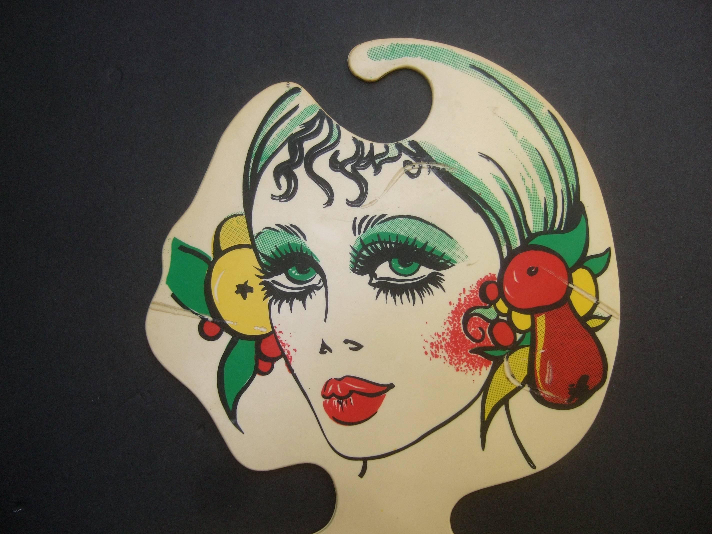 Mod Italian graphic woman plastic hanger c 1970s
The unique retro plastic hanger is illustrated 
with a stylish woman accented with lush
tropical fruits and 1970s style makeup 

Reminiscent of the 1970s Biba style models 

Designed by B D