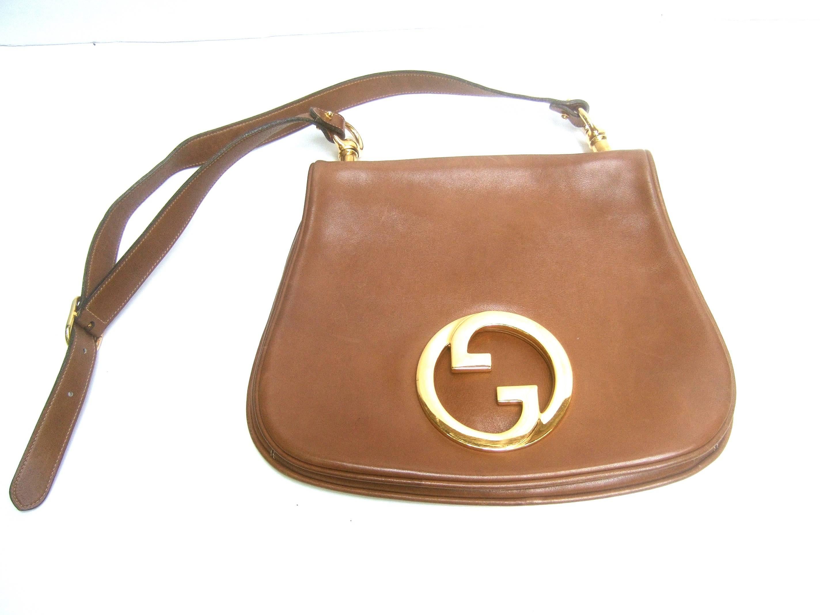 Gucci Italy caramel brown leather blondie shoulder bag c 1970s 
The rare Gucci shoulder bag is designed with supple 
light brown leather

Adorned with Gucci's sleek massive gilt metal 
interlocked initials. Suspended from gilt metal 
hinges.
