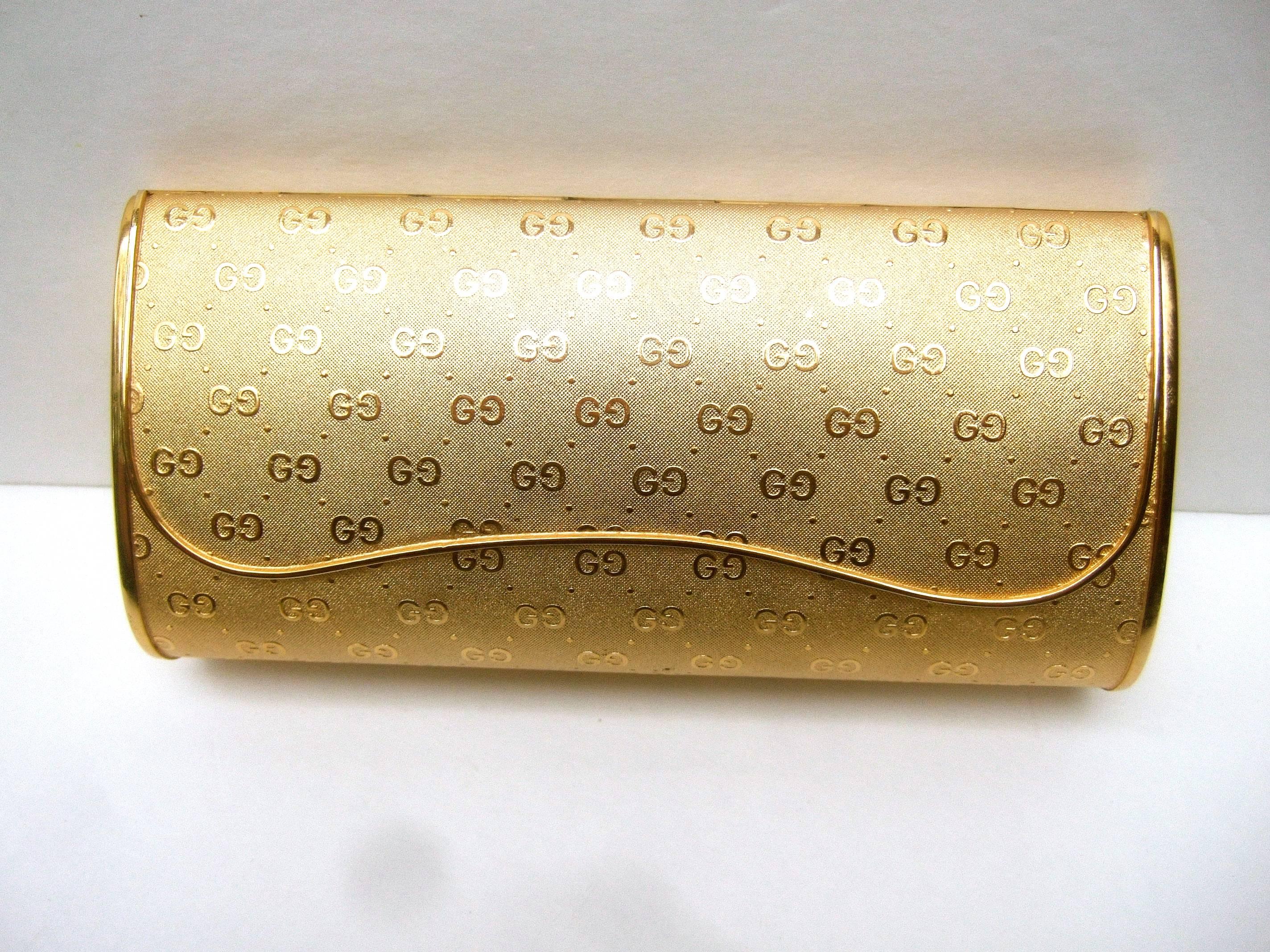 Gucci Italy opulent gilt metal evening clutch bag 
The elegant gold metal minaudiare is designed
with Gucci's initials repeated throughout

The exterior metal has a brushed satin finish
juxtaposed with Gucci's shiny gilt metal initials  
The