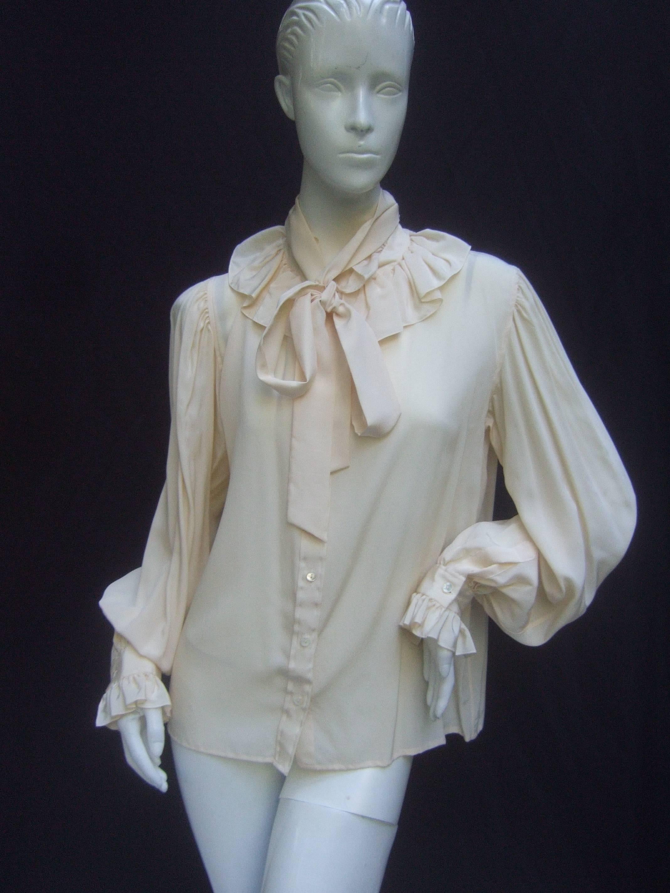 Yves Saint Laurent Rive Gauche Ivory silk ruffled blouse
The classic silk blouse is designed with a ruffled collar
neckline and matching ruffled cuffs

The versatile design has a stationary bow tie that
can be knotted in a billowy bow at the