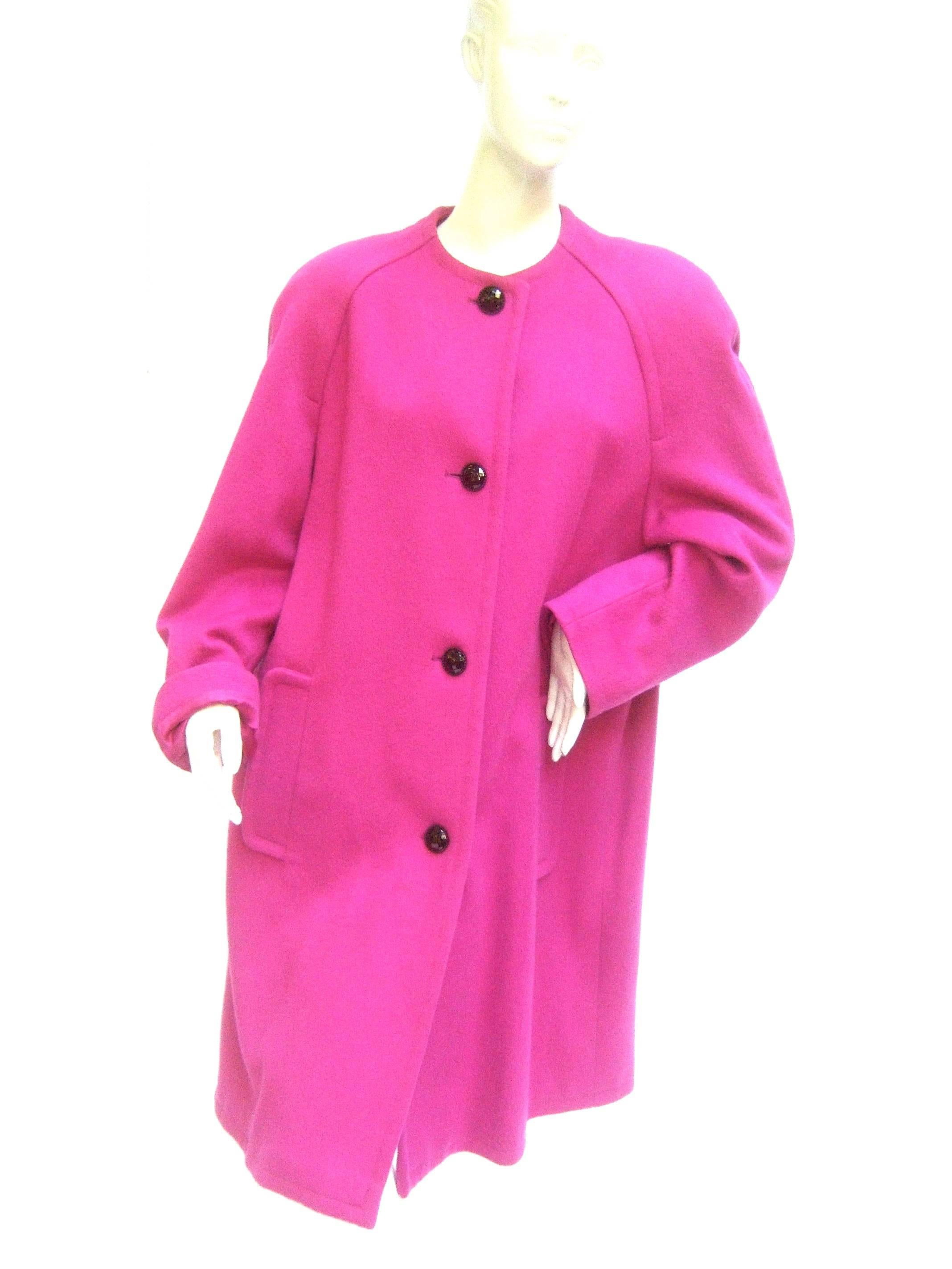 Bill Blass fuchsia wool coat c 1980s
The stylish designer coat makes a striking
bold accessory

Paired with black faceted lucite buttons 
Designed with a pair of pockets on the
front. Lined in fuchsia satin acetate 

The raglan style shoulders have