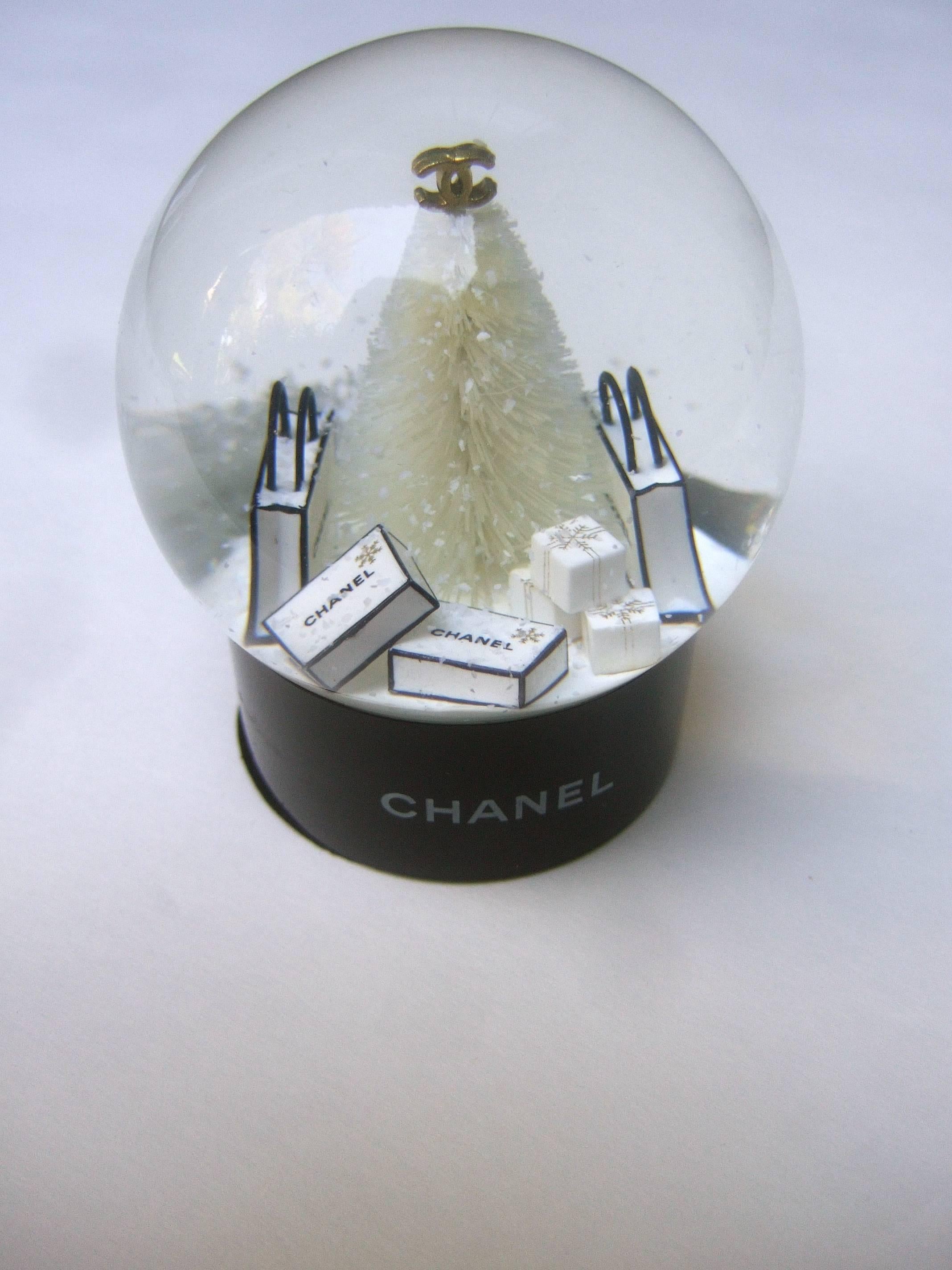 Chanel miniature Christmas tree snow globe 
The stylish crystal orb features a fluffy
white Christmas tree with Chanel's
interlocked gilt initials on the top

Surrounding the white snow covered 
Christmas tree are a collection of
