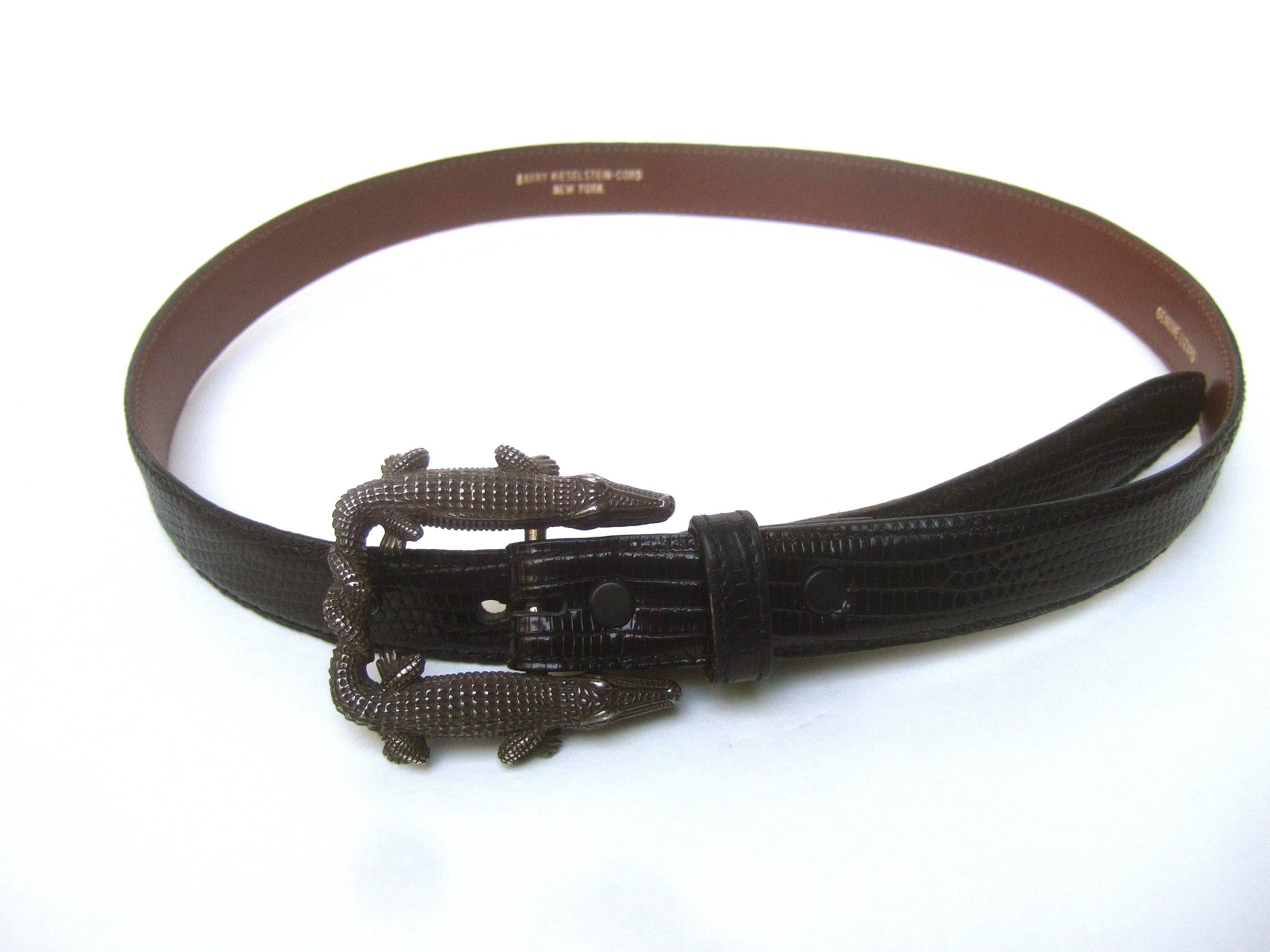 Kieselstein Cord Sterling alligator buckle ebony lizard belt 
The stylish reptile belt is designed with a pair 
of sterling silver stylized alligators with intertwined 
tails 

The sleek lizard skin belt has a slight sheen 
The back side of