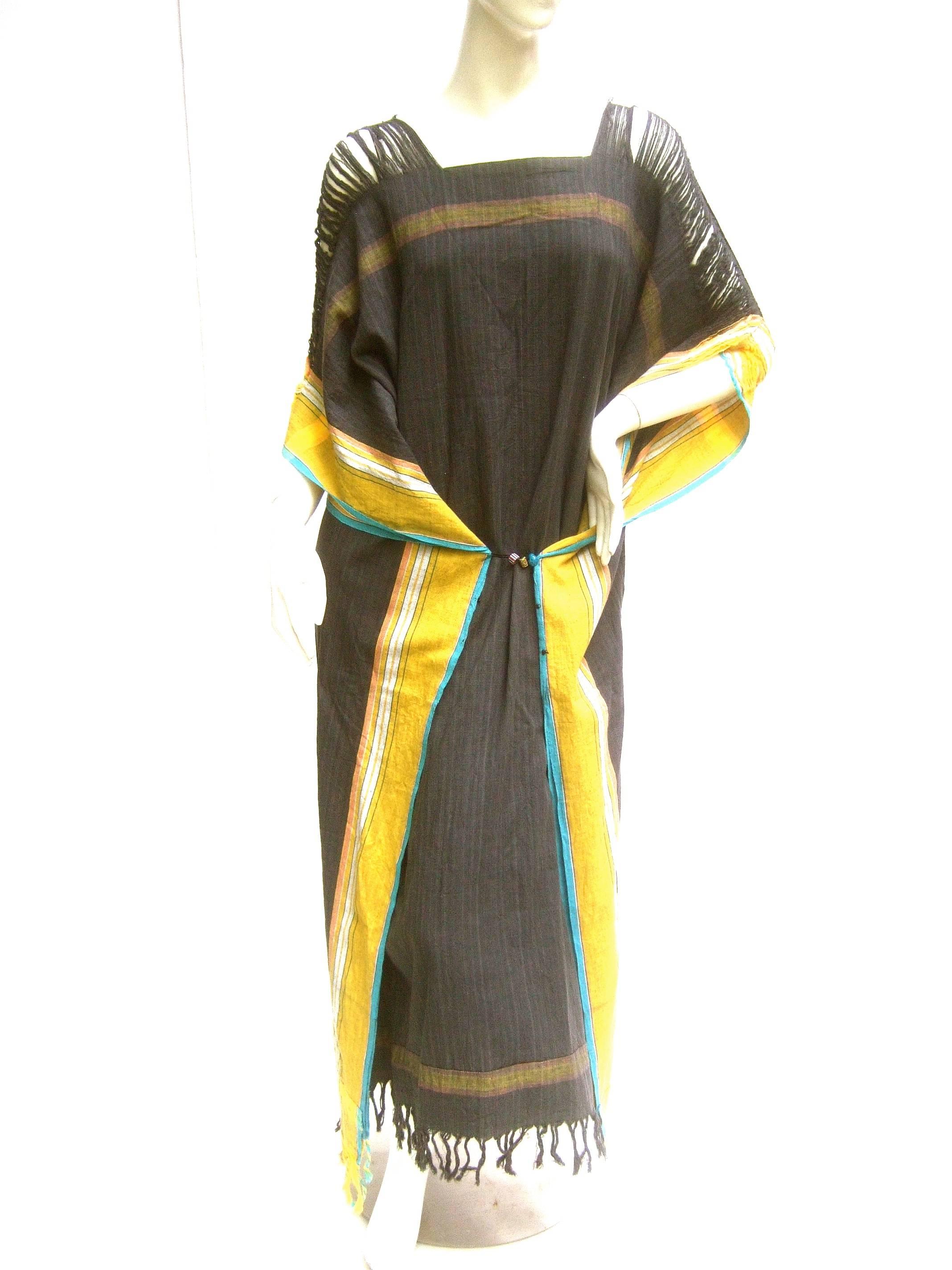South African 1970s cotton ethnic caftan 
The handmade boho style caftan is designed
with shredded shoulders that partially
reveal the skin underneath 

The gray fabric has subtle vertical thin stripes
The sides are accented with bold golden