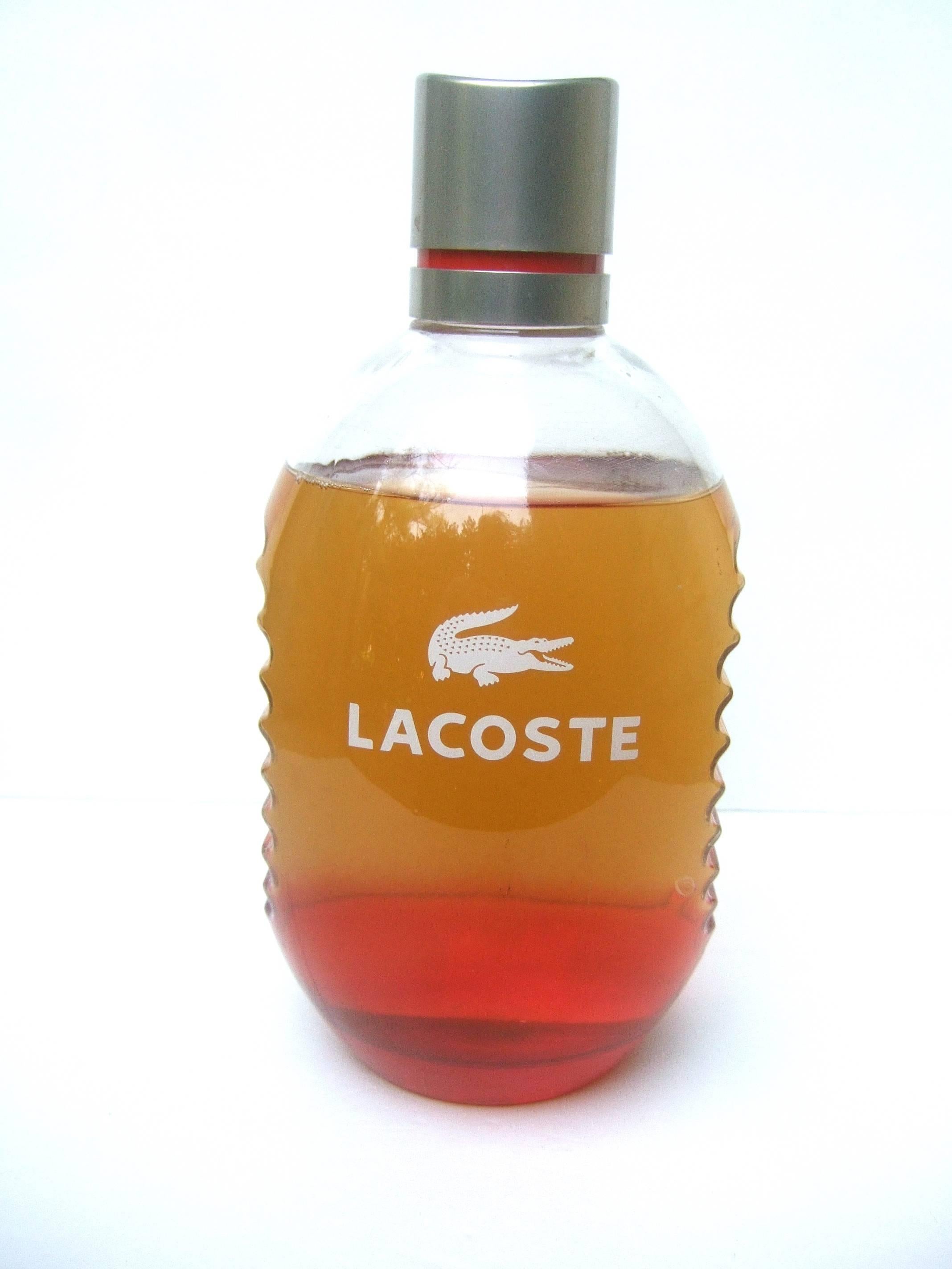 Lacoste huge glass fragrance factice display bottle
The large scale display dummy bottle is filled
with colored water

The glass bottle has Lacoste's white stenciled
name and alligator logo on the front. The sides
of the glass display bottle
