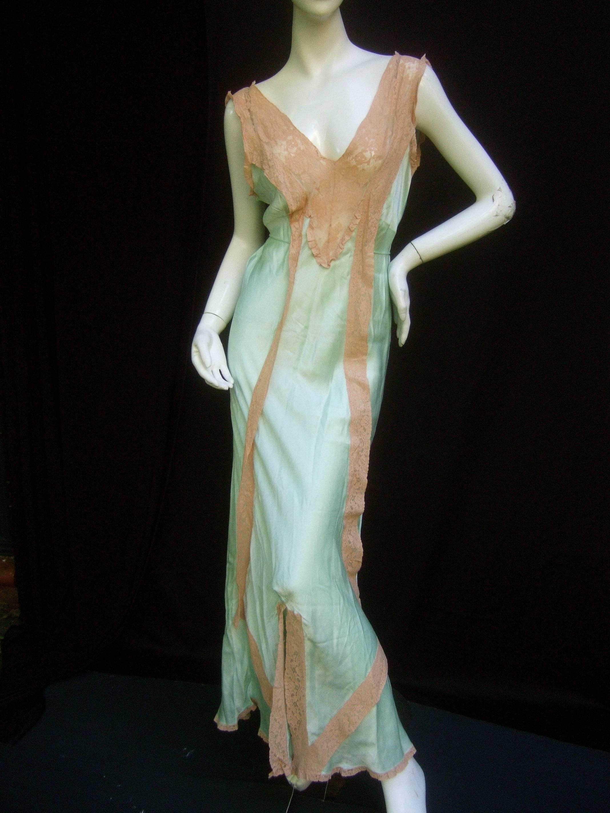 1940s Luxurious mint green silk gown
The vintage silk lingerie gown is designed 
with sumptuous pale green silk

The retro silk gown is accented 
with lace detail on the bodice that
runs down the center and frames 
the hemline 

Reminiscent