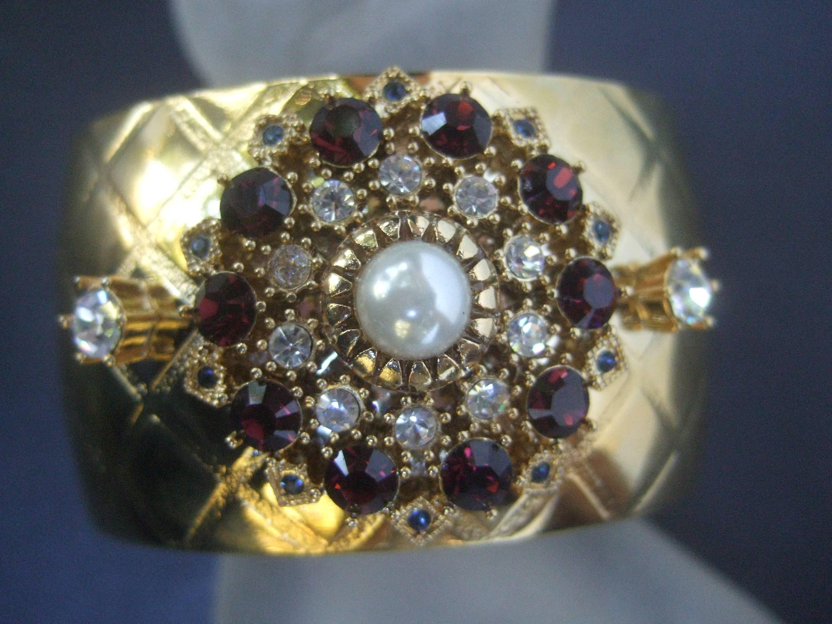 Glittering crystal wide gilt metal cuff designed by Graziano 
The opulent gilt metal cuff bracelet is embellished
with a wreath of garnet color crystals accented
with diamante crystals and tiny smokey gray 
crystals

The gilt metal cuff is