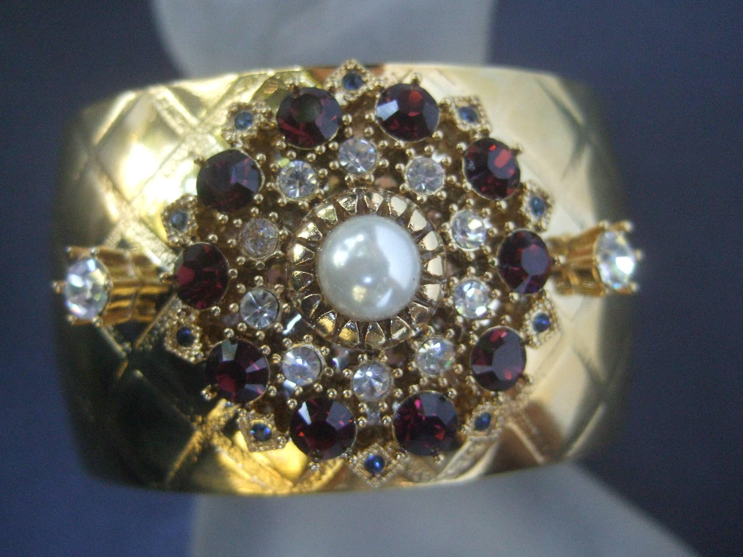 Manchette large en métal doré et cristal scintillant conçue par Graziano 
Ce bracelet opulent en métal doré est agrémenté
avec une couronne de cristaux de couleur grenat accentués
avec des cristaux de diamant et de minuscules gris fumé