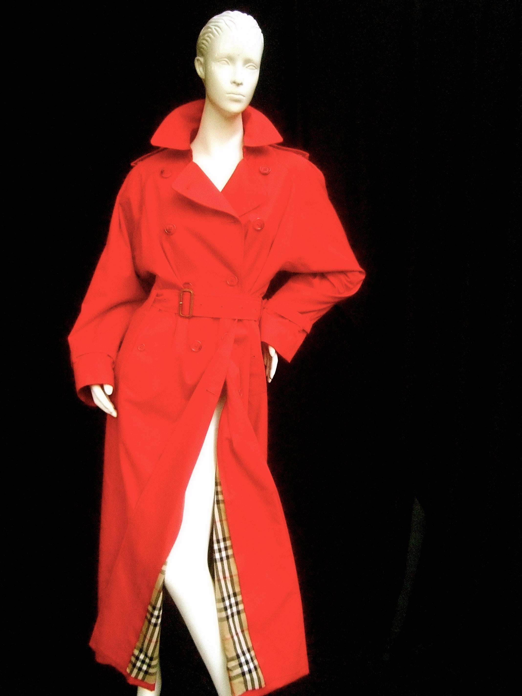 Burberry's Cherry red nova plaid trench coat c 1990s
The classic English trench coat with a bold twist
of vibrant red color

The belted trench coat is lined in Burberry's signature
nova plaid lining. Perfect for Fall or Spring weather 