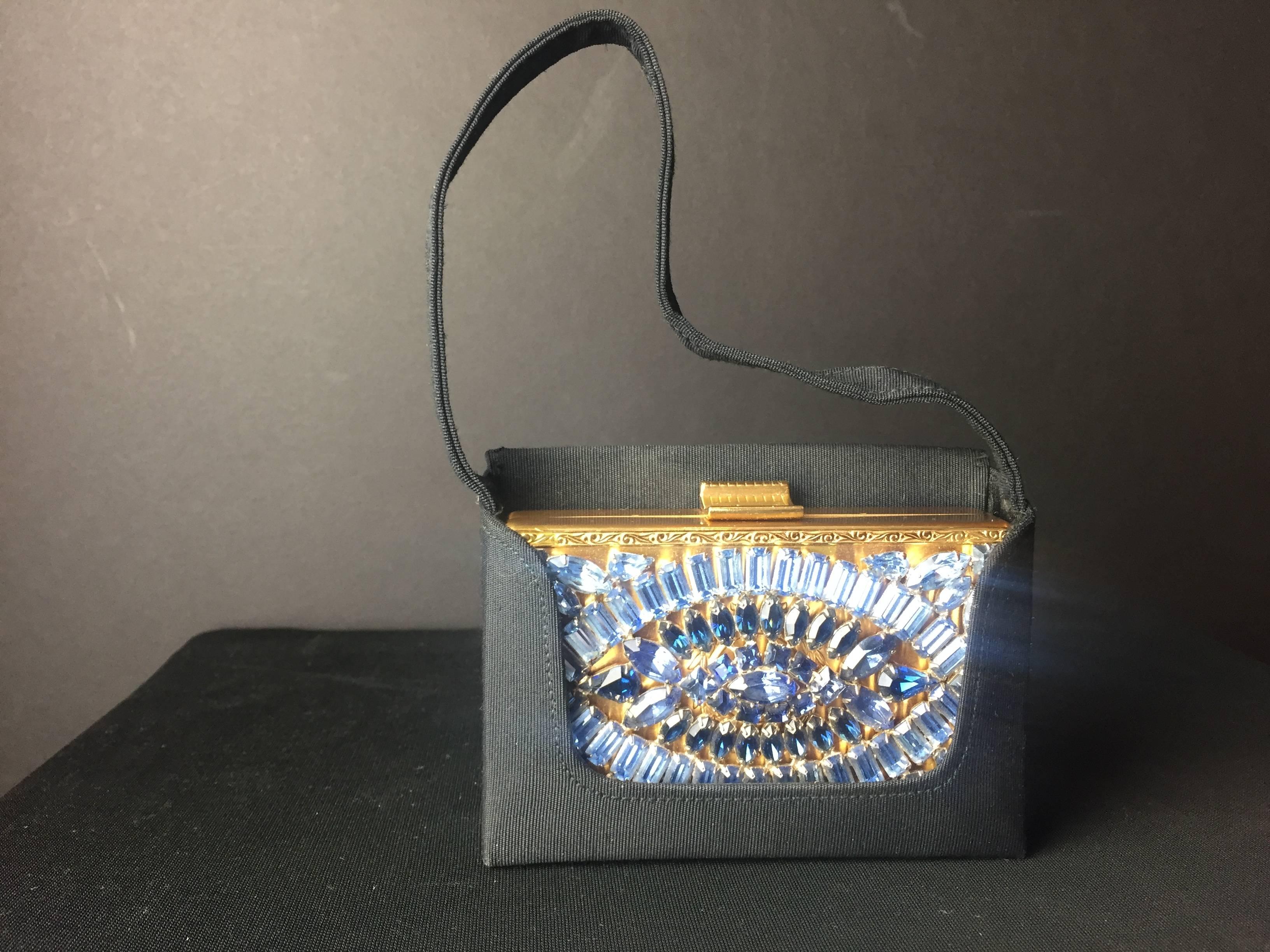 Fantastic evening bag/minaudiere encrusted with faux sapphires and aquamarines arranged in the shape of an eye. Pristine condition. Never used and offered with it's original grosgrain carrying case and box. The interior comprises powder compartment