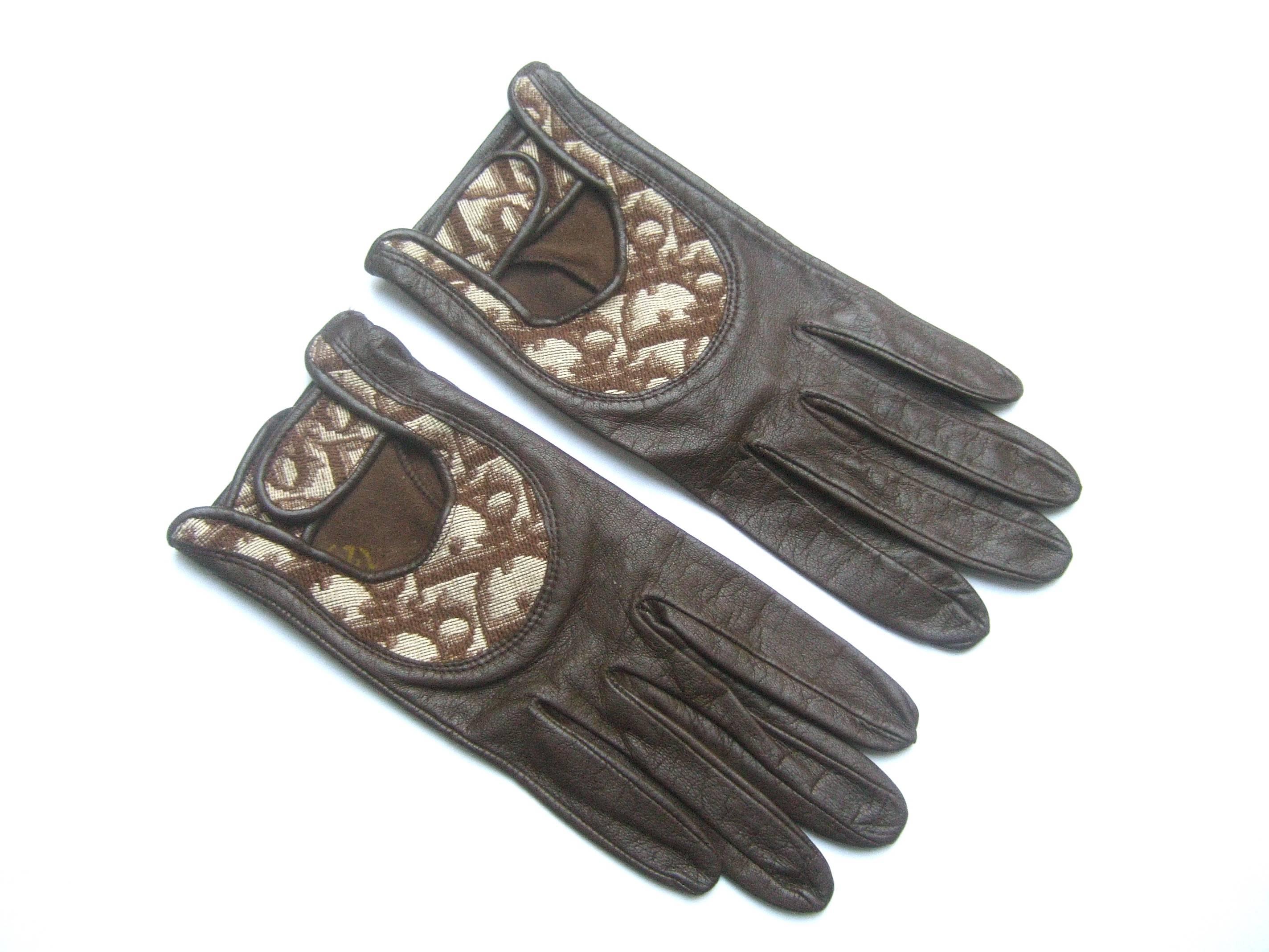 Christian Dior Chocolate brown leather driving gloves c 1970s
The stylish designer gloves are constructed with supple
dark brown leather

The top of each glove has a cloth panel insert with
Dior's name repeated throughout; with a key