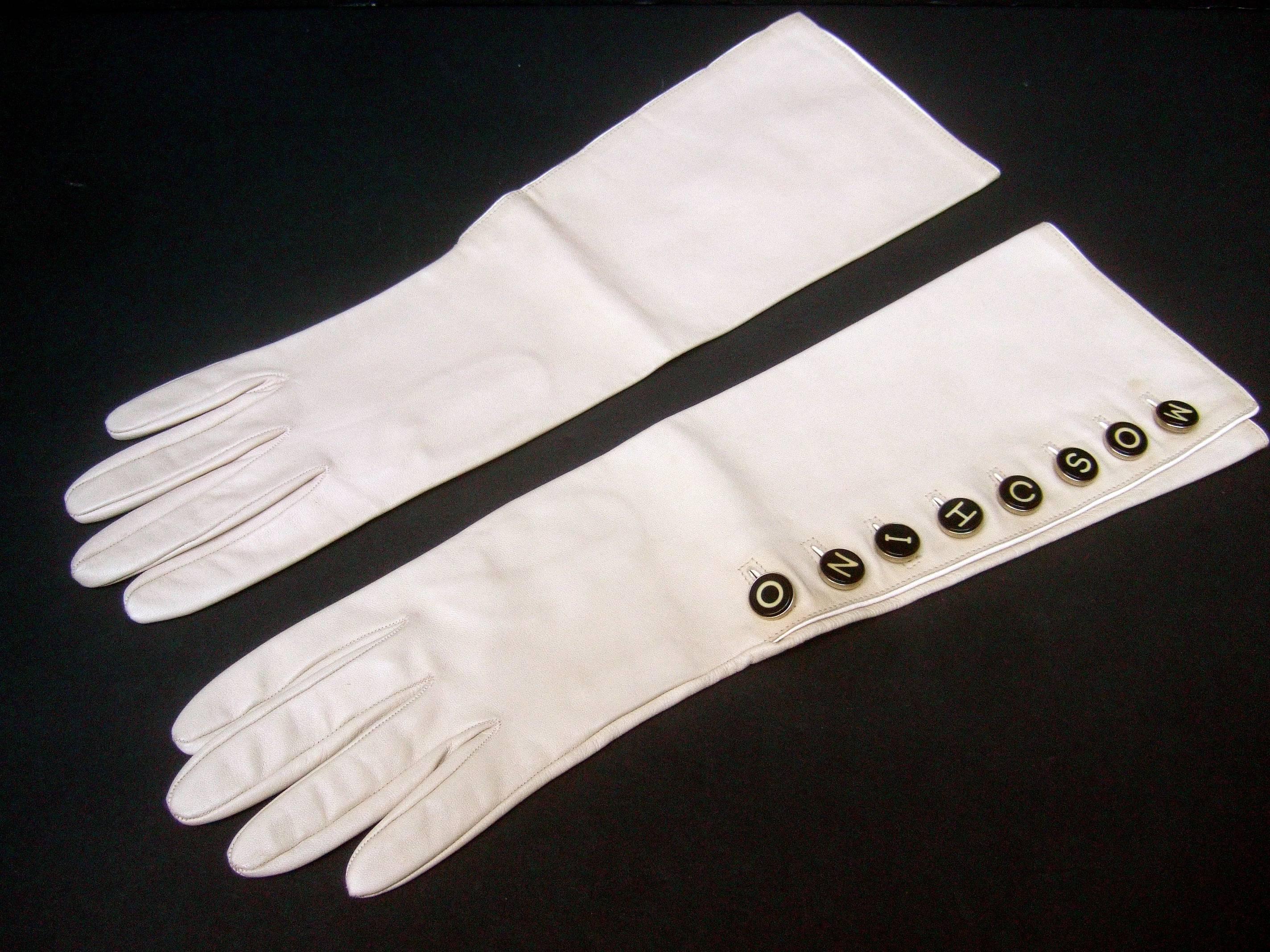 Moschino Chic ivory leather kidskin gloves c 1990s
The Italian leather gloves are designed
with a row of typewriter key style buttons 
on one glove that spells Moschino 

The supple bone color leather elbow length gloves 
are buttery soft &