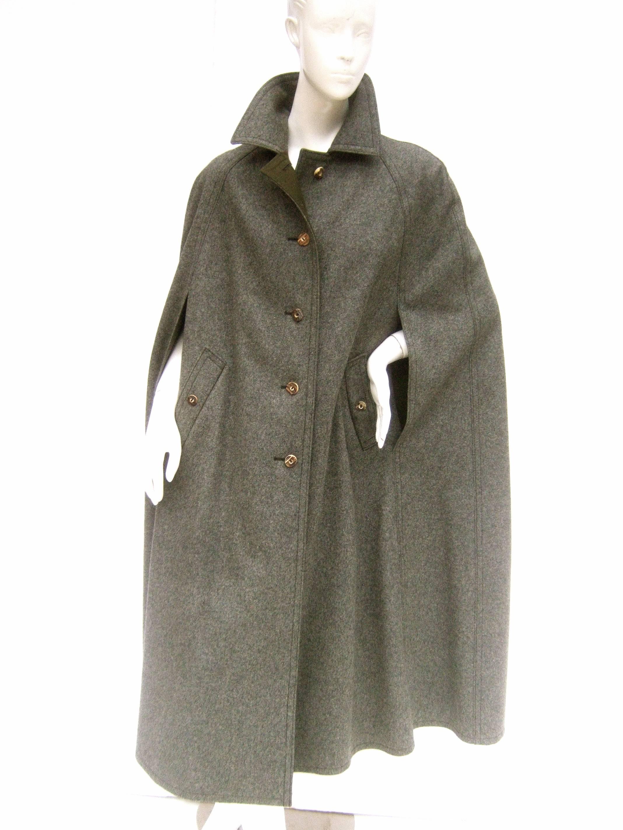 Classic gray flannel wool Austrian cape c 1980s
The stylish wool cape is accented with rustic resin 
horn style buttons 

Designed with slit seams to place the arms thru 
There are a pair of buttoned covered diagonal 
pockets on both front