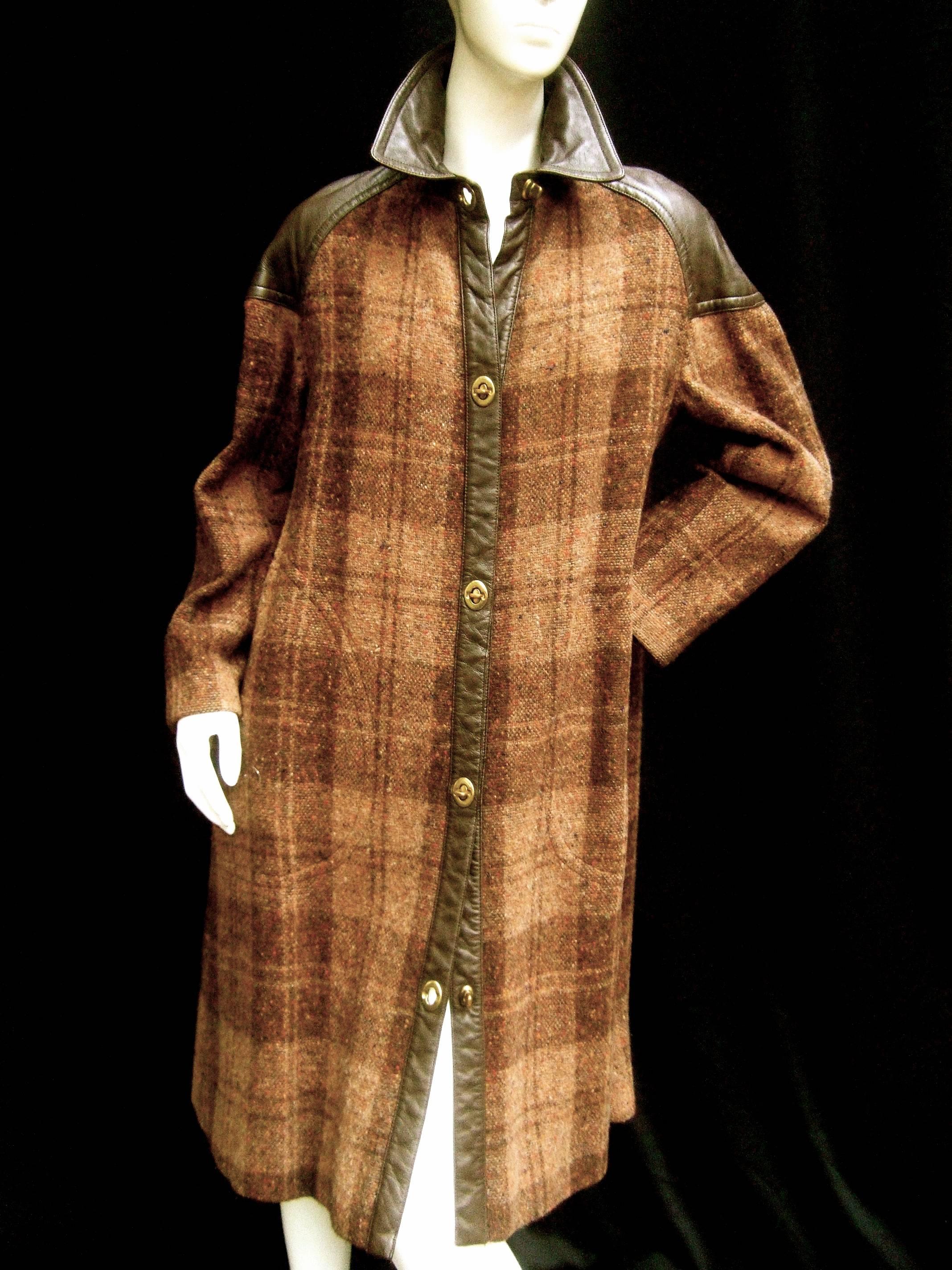 1970s Brown plaid leather trim wool coat 
The classic coat is designed with two tone
brown window pane wool; accented with 
chocolate brown leather trim on the collar,
shoulders, trim on the opening that extends 
to the pockets 

The unique