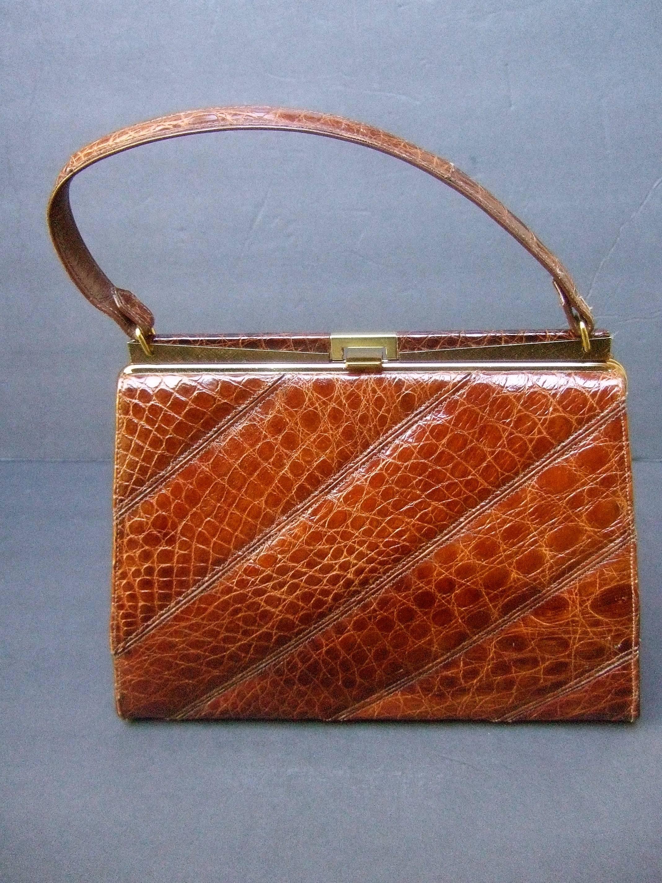 Chic genuine brown alligator handbag ca 1960s
The stylish retro handbag is covered with exotic
alligator skin that extends to the handle & clasp 

Accented with sleek gilt metal hardware
The interior is lined in ivory color vinyl 
designed with a