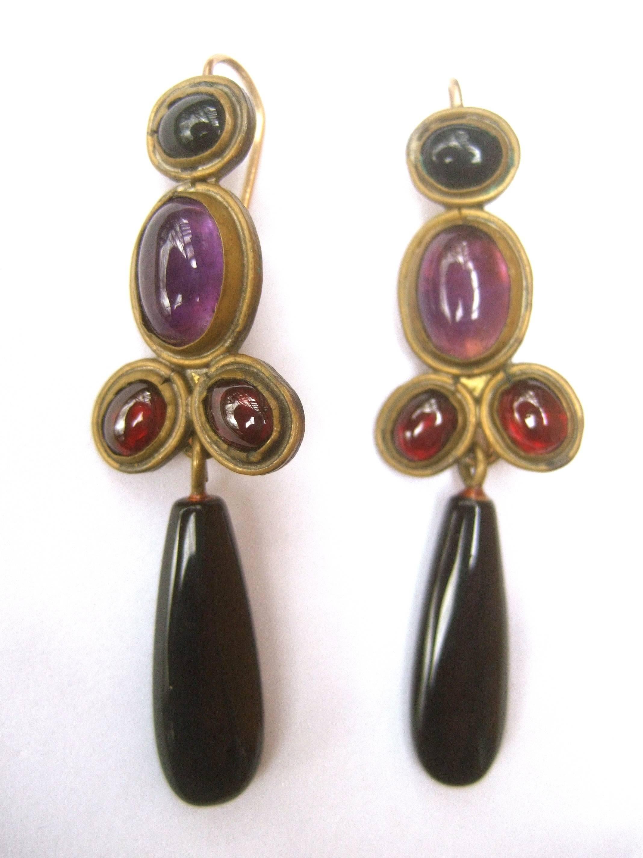 Opulent artisan semi precious dangle earrings by Karen Seberi 
The elegant handmade pierced dangle earrings are designed
with a collection of amethyst, garnet and jet semi precious
translucent smooth cabochons 

The stones are set in brass metal