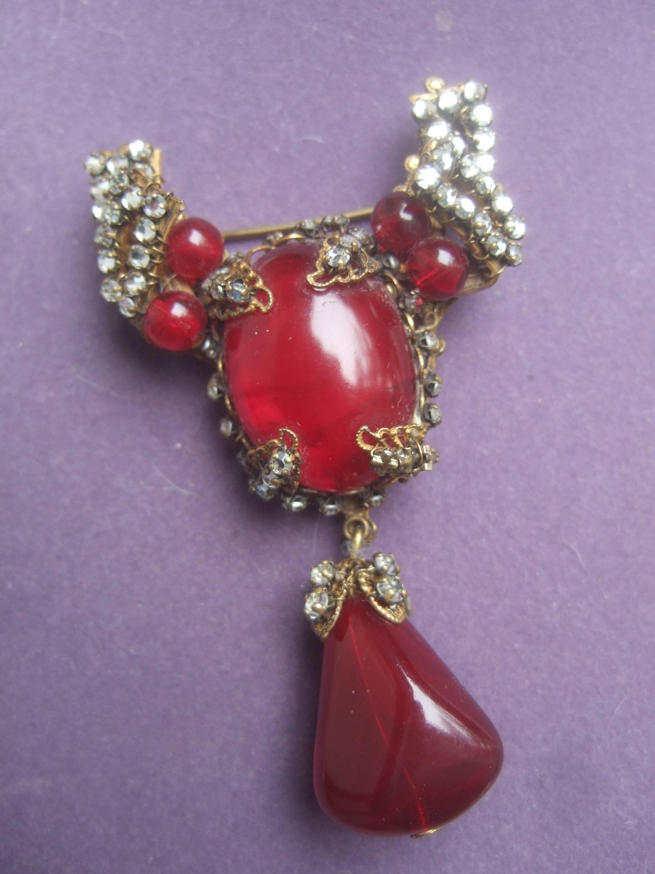 Miriam Haskell Exquisite scarlet glass tear drop brooch ca 1950s
The designer costume brooch is adorned with a large
oval glass deep red cabochon in the center

Dangling from the ornate brooch is a matching red glass
cabochon. The intricate filigree