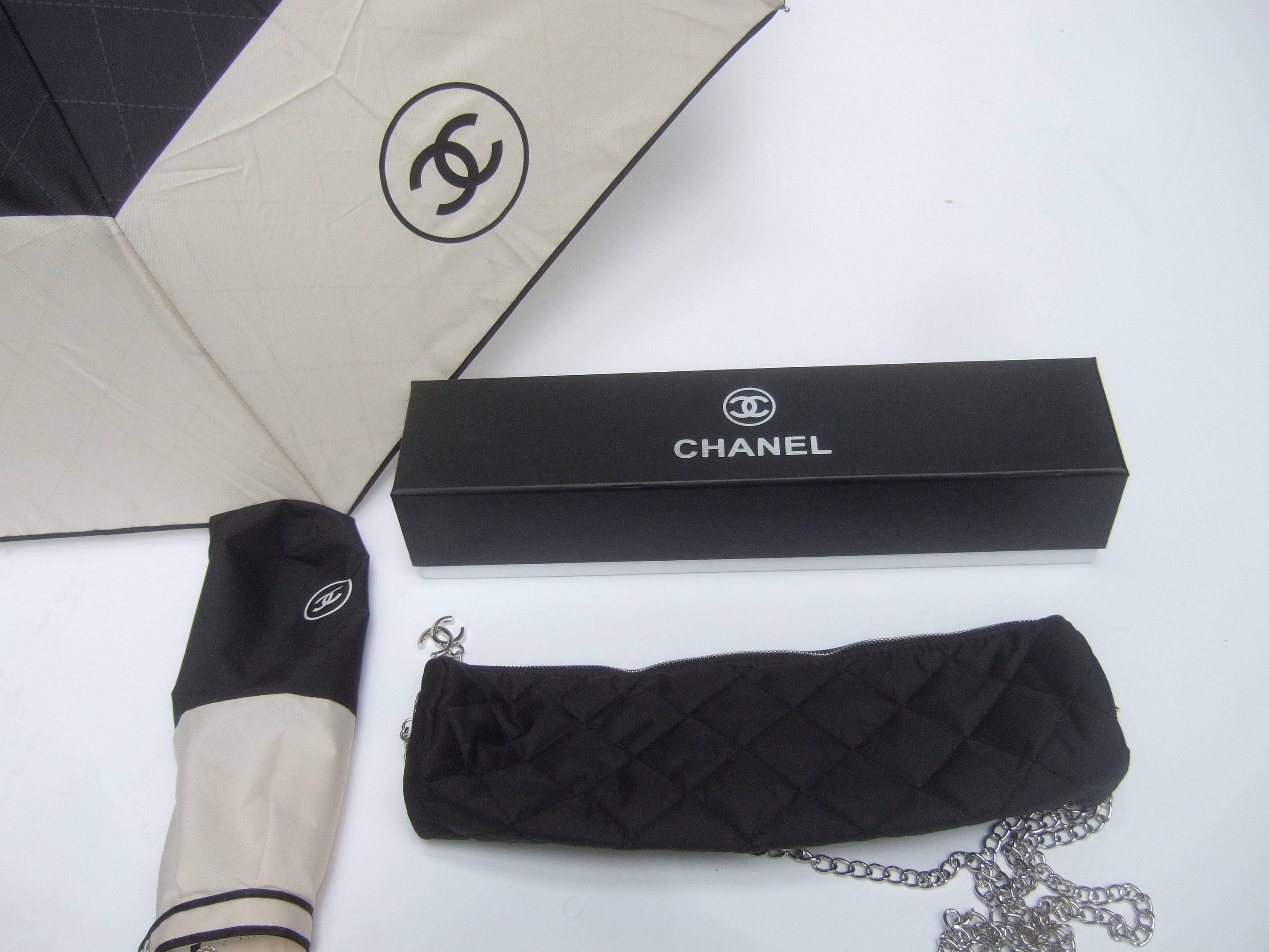 Chanel stylish black and ivory nylon umbrella in Chanel box
The chic umbrella comes with a quilted nylon carrying case 
on a silver metal chain strap. The umbrella can be carried in the
black quilted carrying case. The quilted nylon case has a