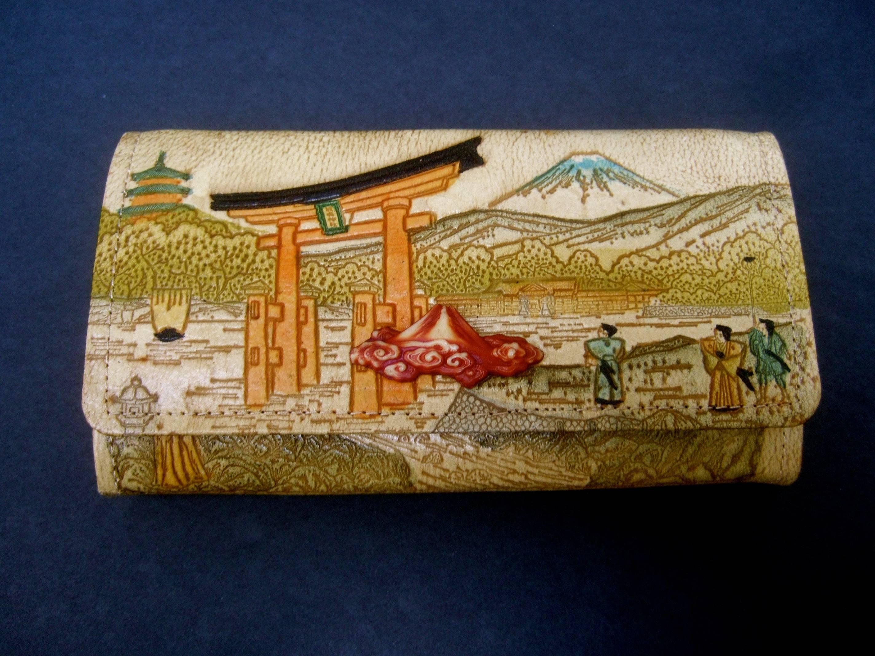 Exotic Japanese tooled leather clutch / wallet ca 1960
The unique clutch / wallet is decorated with a tooled 
leather scene illustrated with Japanese iconography;  
ceremonial figures, a pagoda structure and mountain peaks   

The tooled leather