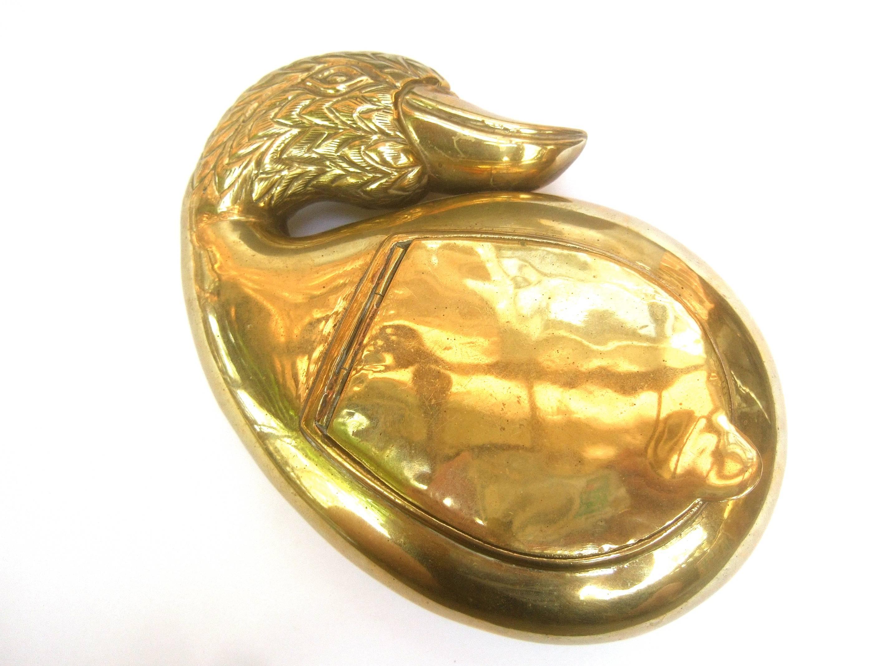 Exotic brass metal bird evening bag c 1990s
The sleek brass metal clutch purse
is designed in the shape of a stylized 
bird

The bird's head has etched metal designs
that emulate feathers with an elongated 
beak 

The back exterior side is designed