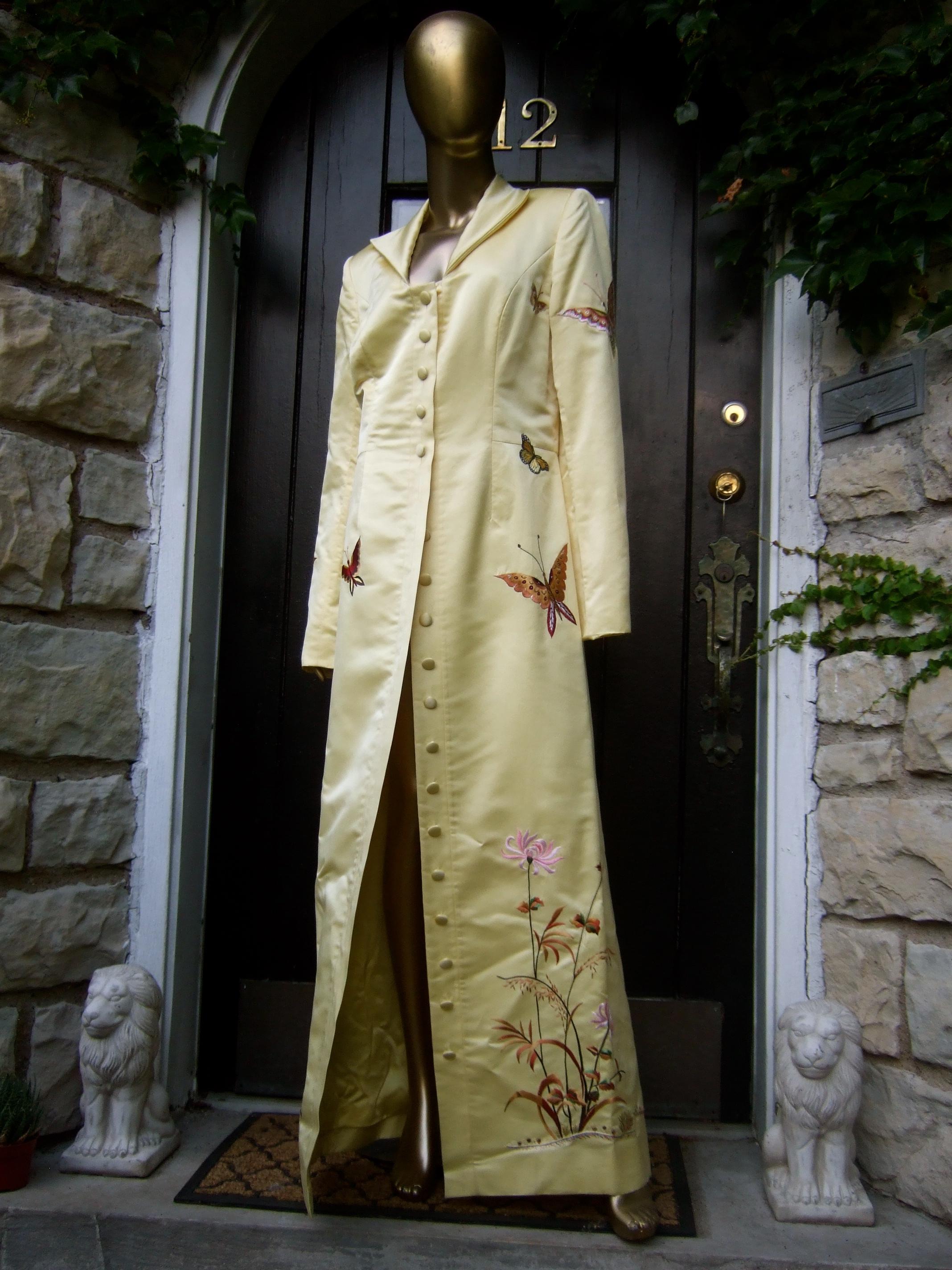 Manteau d'opéra et de soirée en satin duchesse brodé de papillons, d'un jaune ravissant, C.C. années 1970
Ce magnifique manteau d'opéra est réalisé en satin jaune bouton d'or pâle
Le somptueux satin est agrémenté d'un jardin de papillons brodés à la