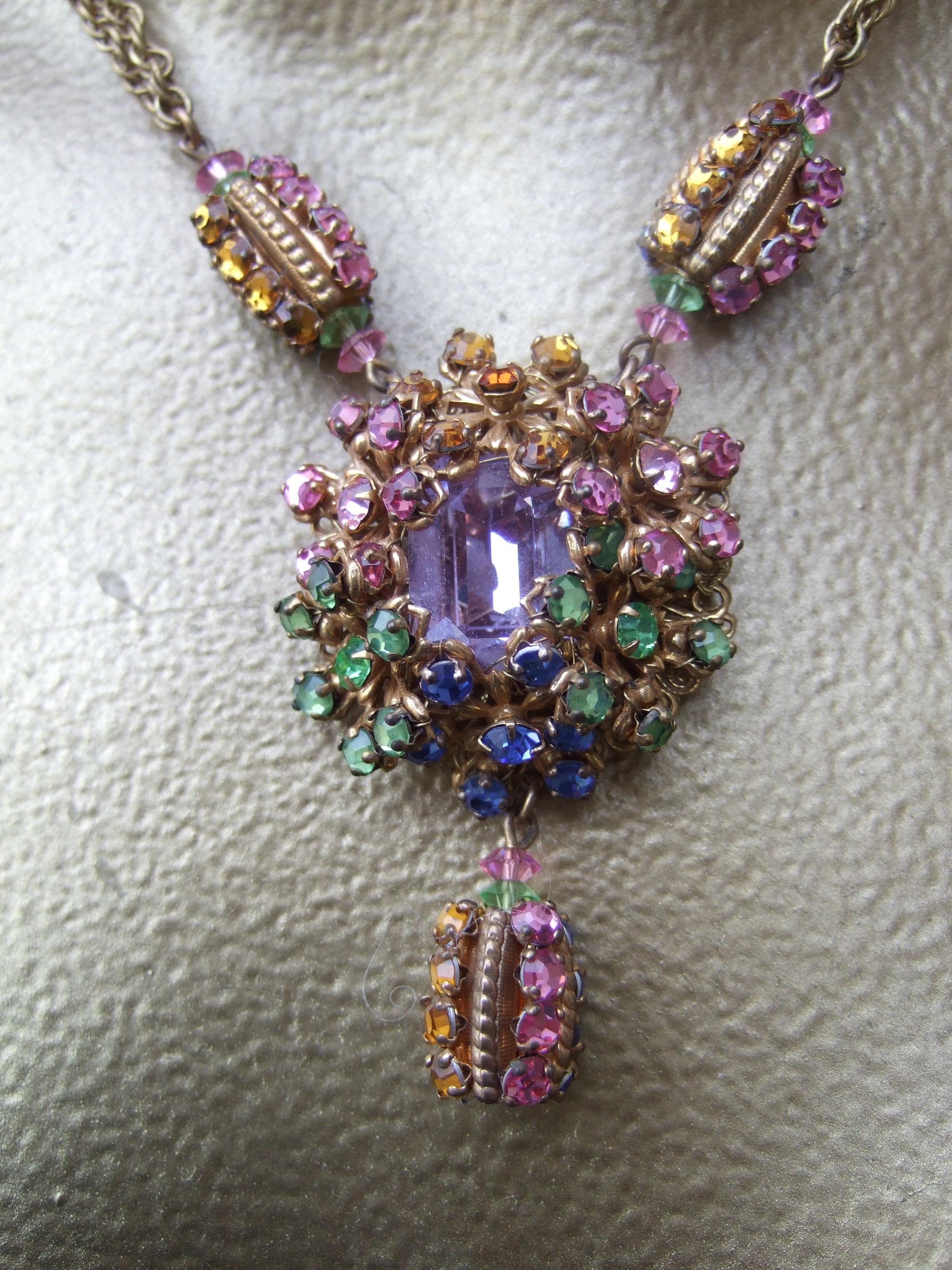 MIRIAM HASKELL Opulente Halskette mit pastellfarbenem Kristallanhänger und passende Ohrringe mit Clip um 1960
An der Meta-Kette aus Messing hängt ein ovaler Anhänger mit einem großen lavendelfarbenen Kristall. 
umrahmt mit Büscheln von glitzernden