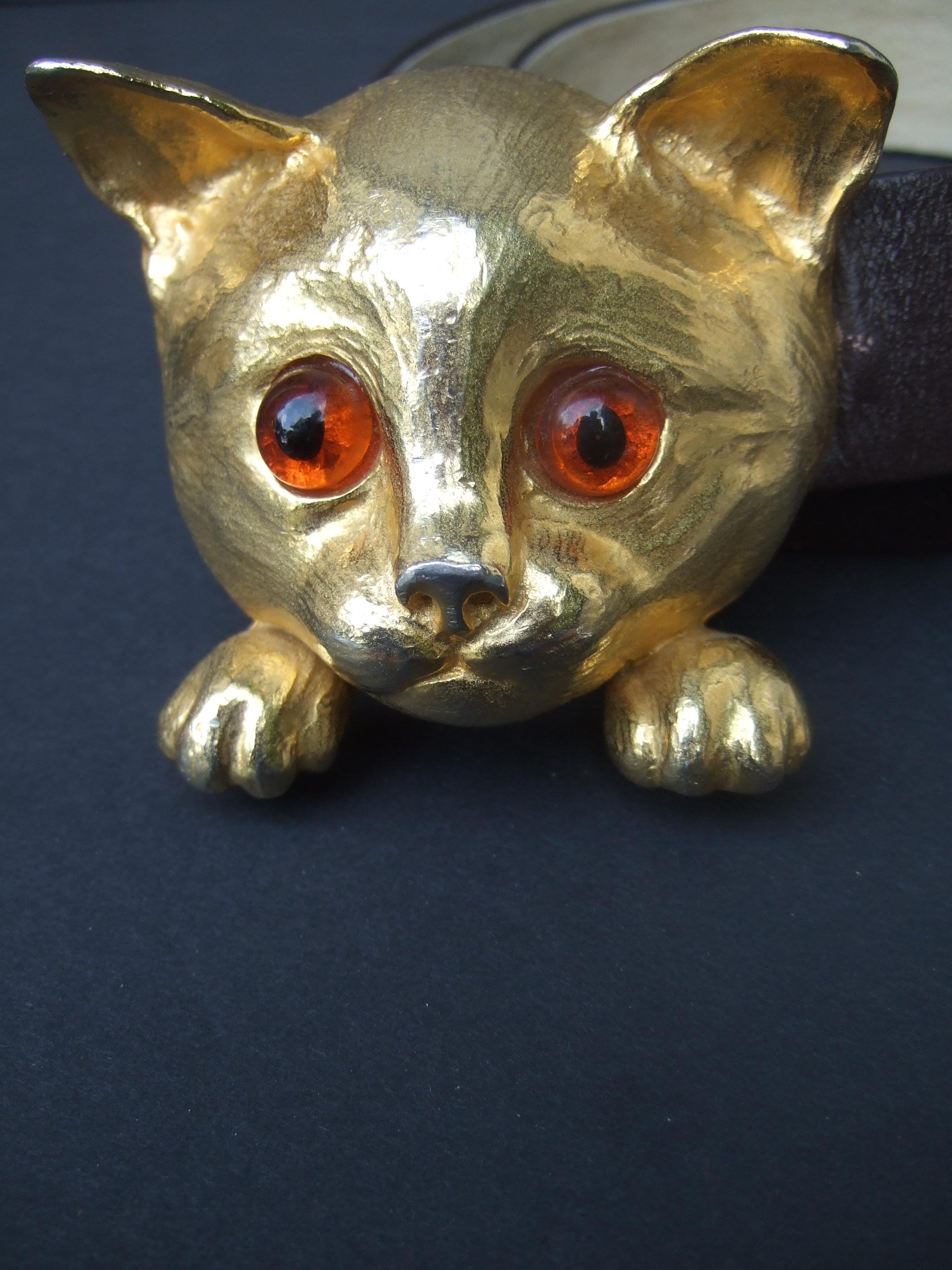 CHRISTOPHER ROSS Encantador cinturón con hebilla felina de metal dorado a gran escala c 1976
La entrañable hebilla de gato está adornada con curiosos ojos de cabujón de cristal color ámbar 
Se combina con un cinturón de cuero marrón liso que se