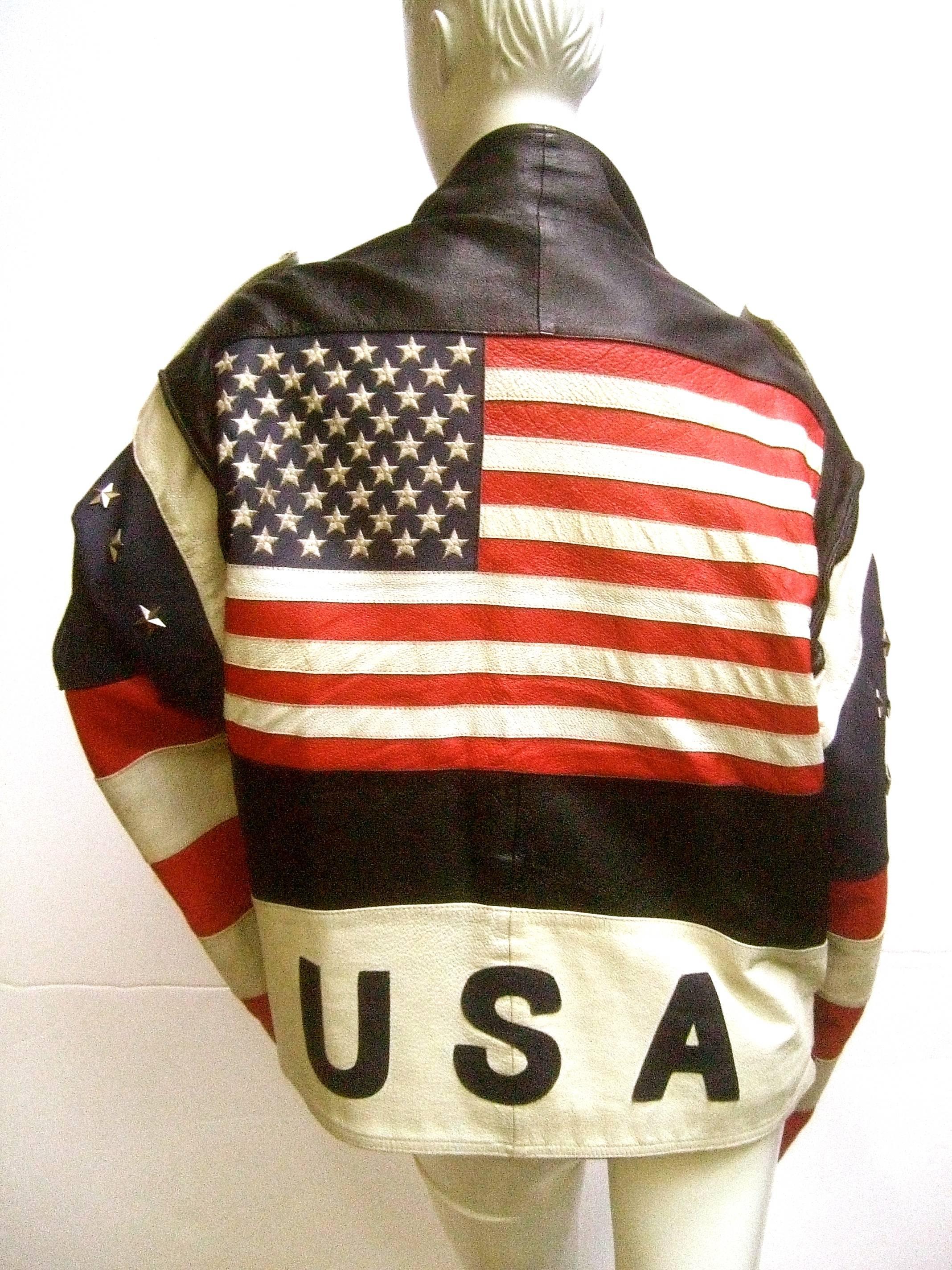 Men's Leather patriotic american flag motorcycle jacket ca 1980s
The unique leather jacket is deigned with the American flag
across the back side. Underneath the flag in bold block
letters reads USA. The patriotic theme is evident throughout
the