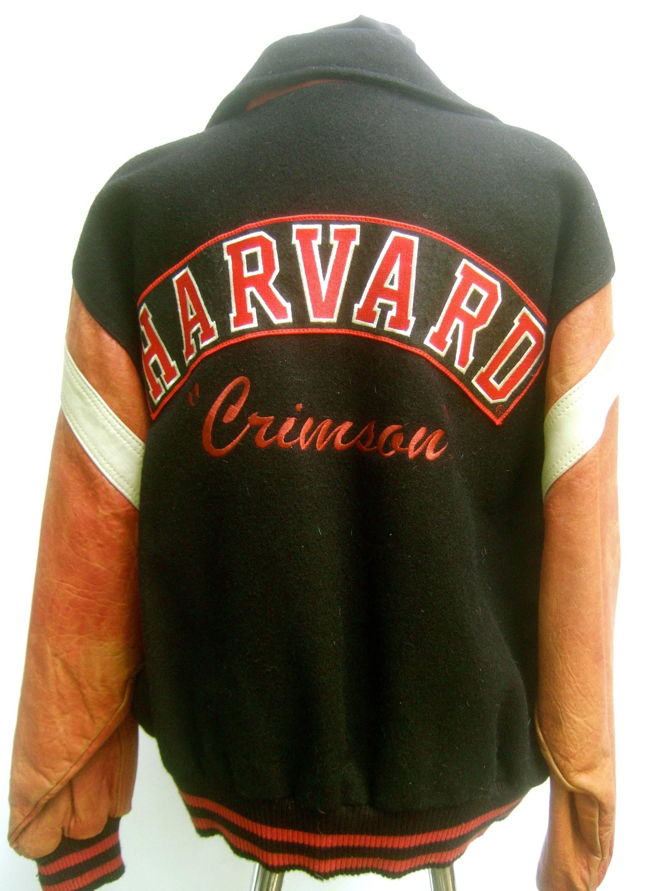 Harvard Leather and wool collegiate jacket ca 1980s
The backside of the black wool jacket has an
applique embroidered patch labeled Harvard
Underneath is embroidered Crimson in script 

The front of the black wool chest has an appliqué 
embroidered