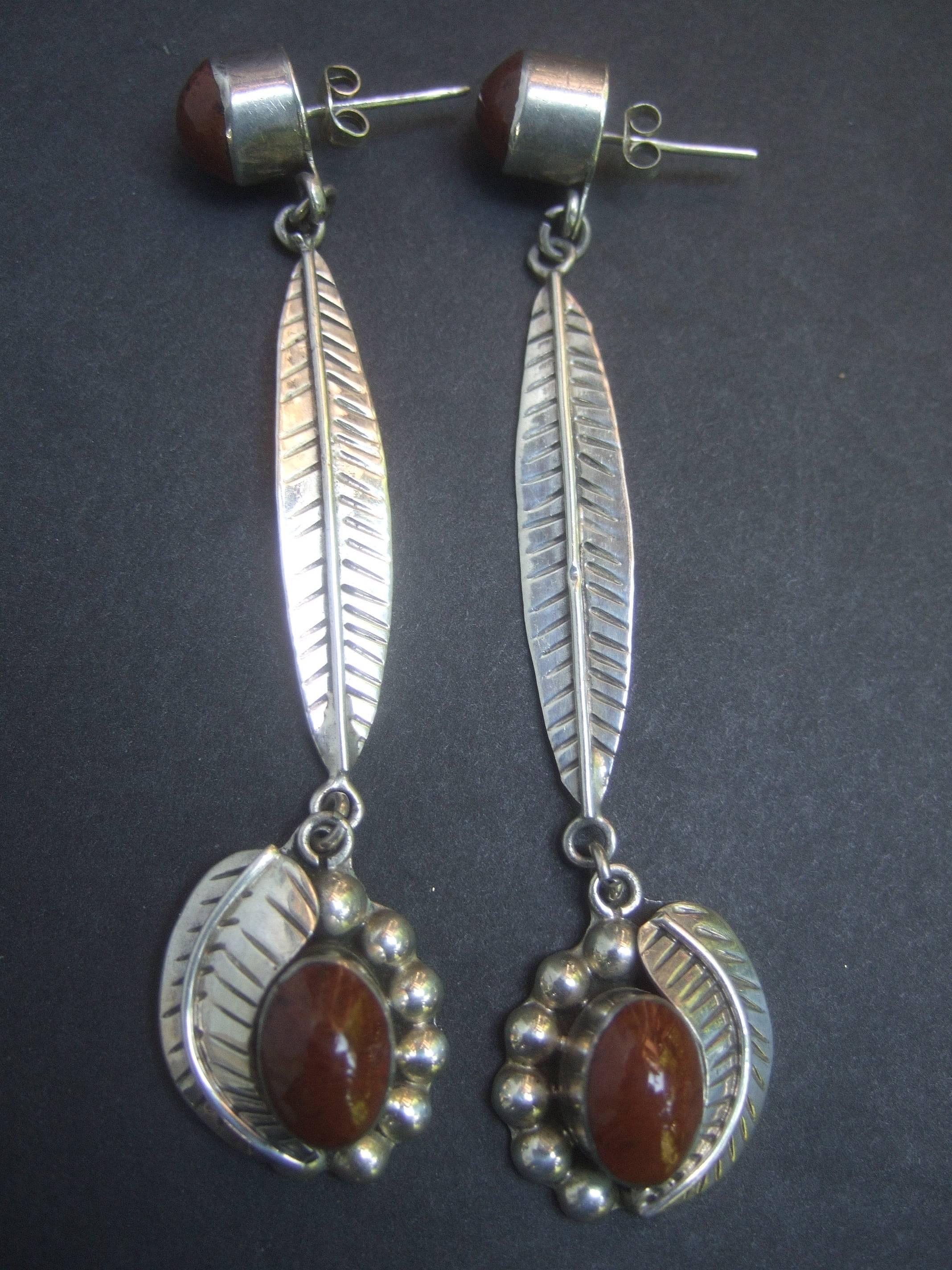 Sterling artisan Mexican statement earrings ca 1980s 
The unique large scale pierced earrings are designed
with elongated etched sterling bands in a leaf pattern

Dangling from the base of the earrings are bezel set 
brown opaque smooth stones