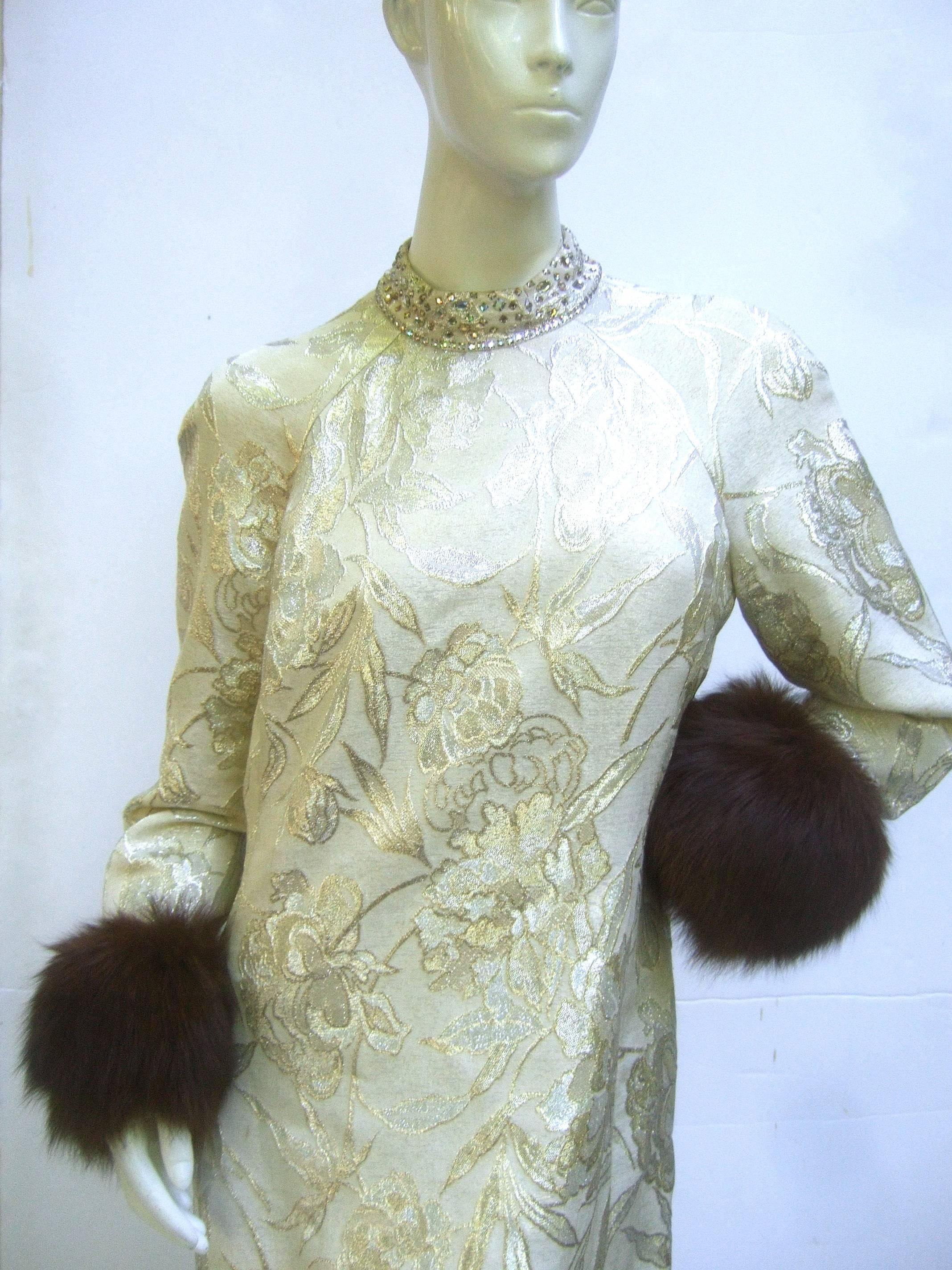 Saks Fifth Avenue Champagne brocade fox trim gown c 1970
The elegant metallic brocade gown is embellished with
a glittering diamante crystal jeweled collar 

The sumptuous metallic brocade fabric is a lush garden 
of silver flowers with subtle hints