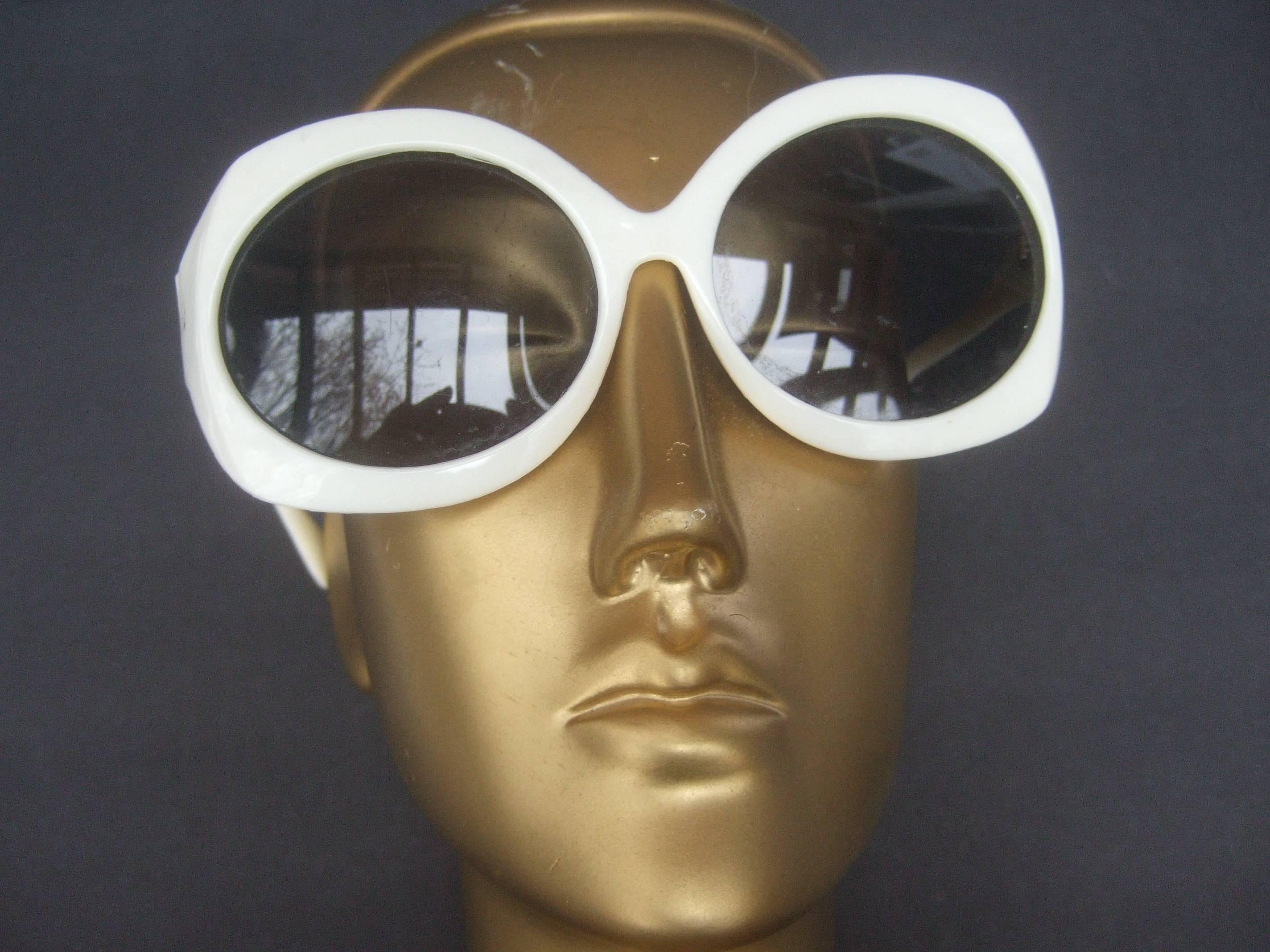 Mod Italian sleek white plastic sunglasses ca 1970
The stylish retro sunglasses are designed with 
tinted gray plastic large scale lenses 

The bold frames are shiny white plastic 
Makes a very chic sporty summer or resort
wear accessory

Designed
