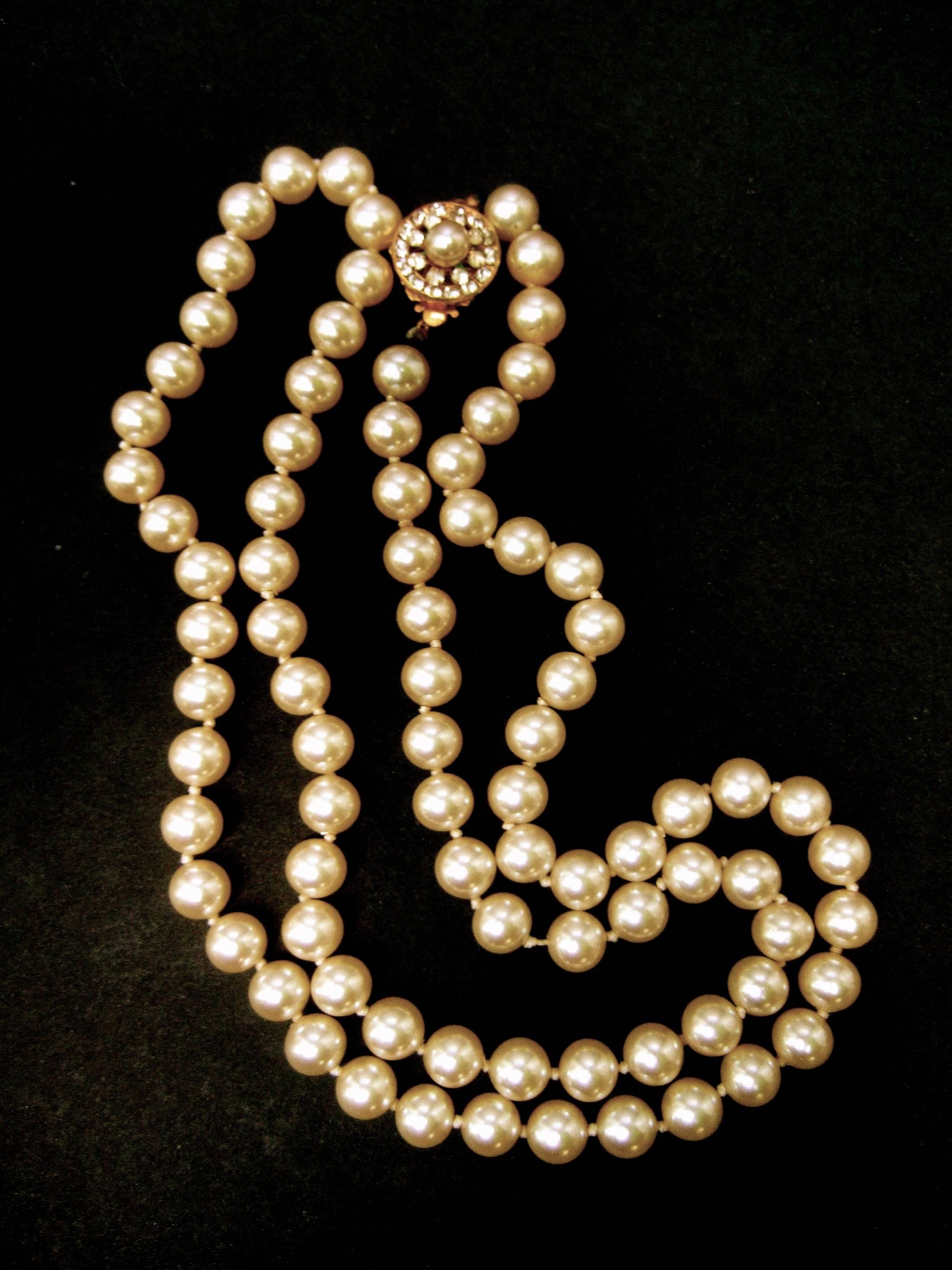 Miriam Haskell Opulent glass enamel pearl long necklace ca 1970
The chic costume pearl necklace is designed with rows 
of lustrous smooth glass pearls 

The circular gilt metal clasp is encrusted with a wreath of tiny   
glittering diamante
