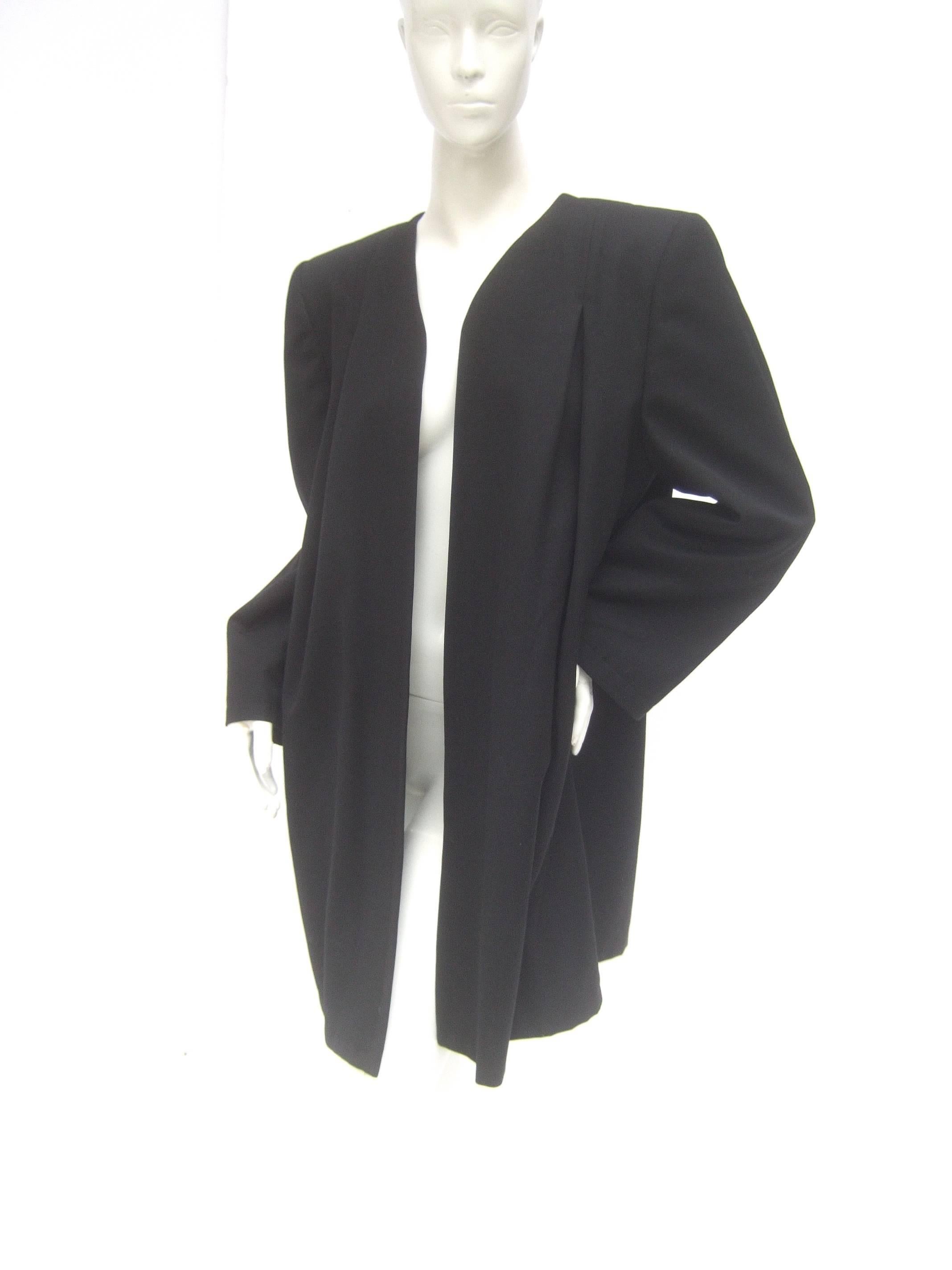 Valentino Italian light weight black wool duster jacket c 1980s
The elongated black jacket makes a chic timeless garment 

Designed with a subtle single partial vertical pleat that runs
down both sides of the front. Designed without buttons
or
